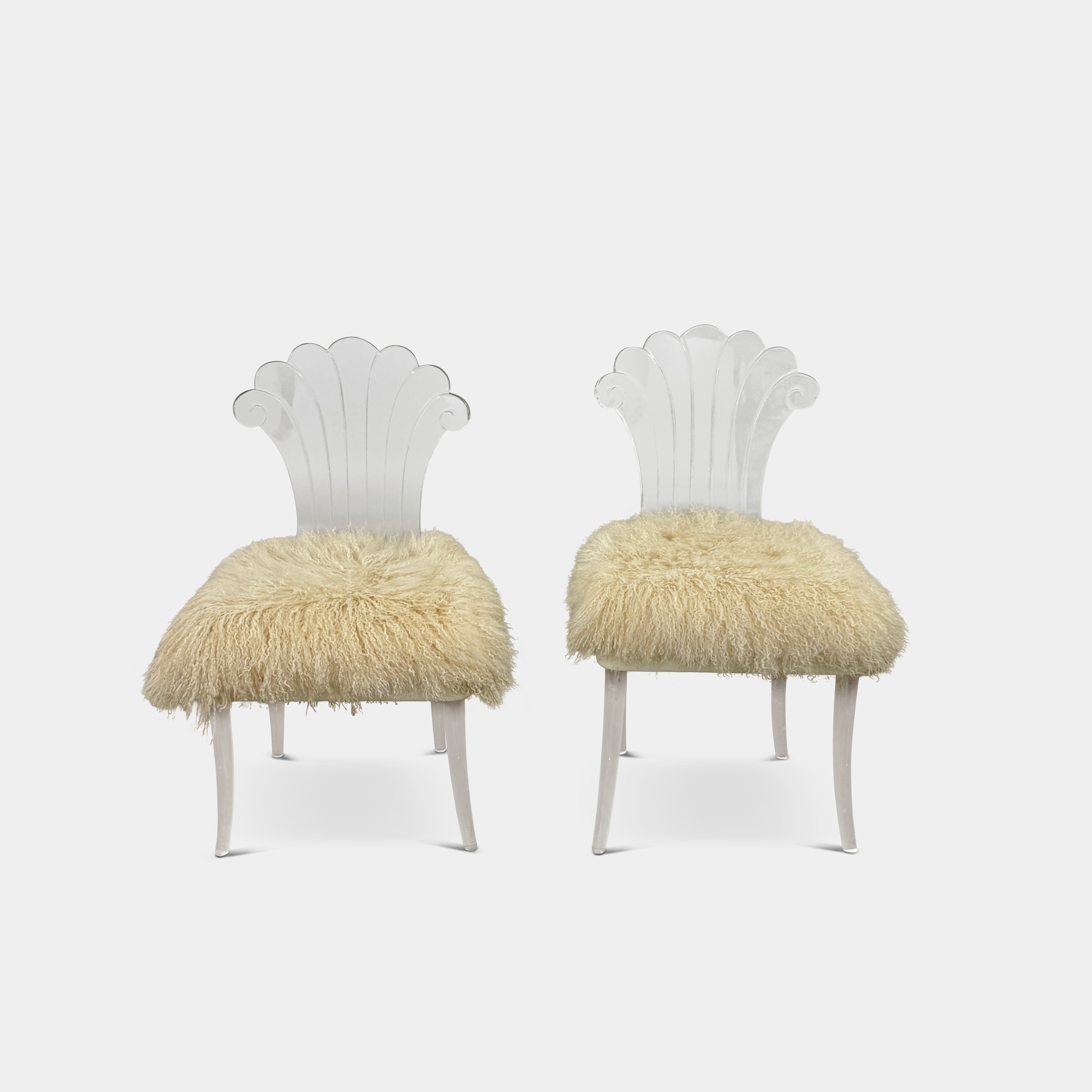 Two white Vintage Elsie de Wolfe Lucite Chairs with elegant fan-shaped backs and plush beige sheepskin seats are displayed against a plain white background.