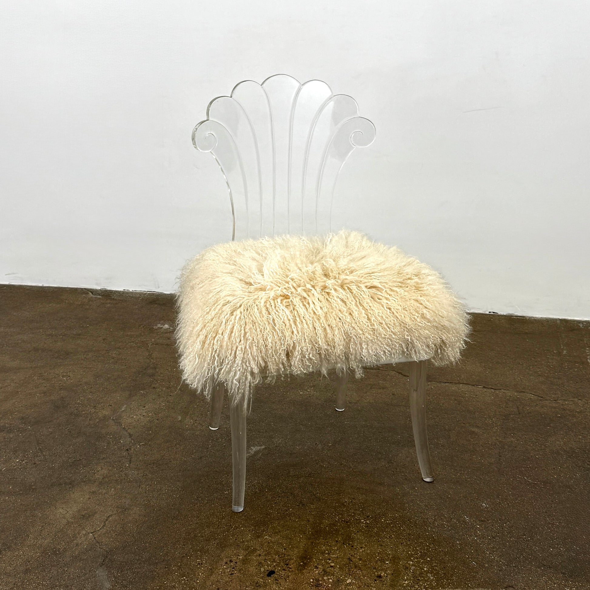 Two white Vintage Elsie de Wolfe Lucite Chairs with elegant fan-shaped backs and plush beige sheepskin seats are displayed against a plain white background.