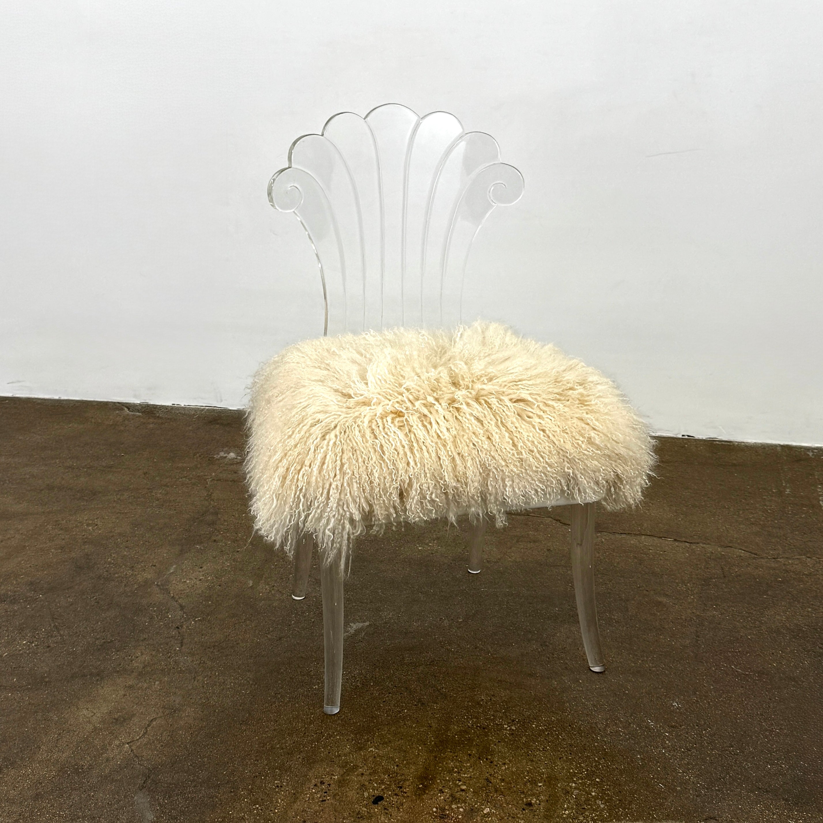 Two white Vintage Elsie de Wolfe Lucite Chairs with elegant fan-shaped backs and plush beige sheepskin seats are displayed against a plain white background.