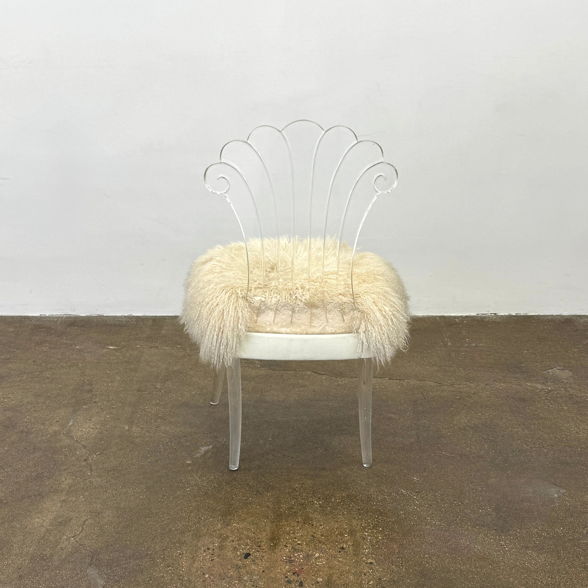 Two white Vintage Elsie de Wolfe Lucite Chairs with elegant fan-shaped backs and plush beige sheepskin seats are displayed against a plain white background.