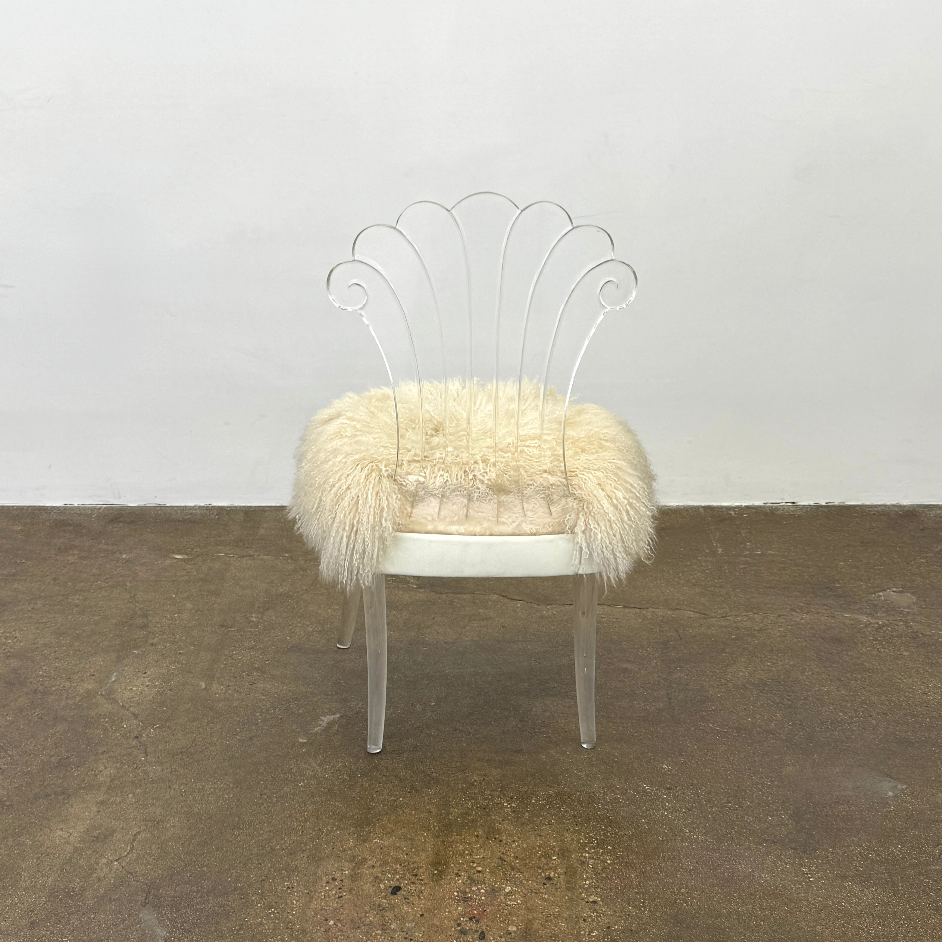 Two white Vintage Elsie de Wolfe Lucite Chairs with elegant fan-shaped backs and plush beige sheepskin seats are displayed against a plain white background.