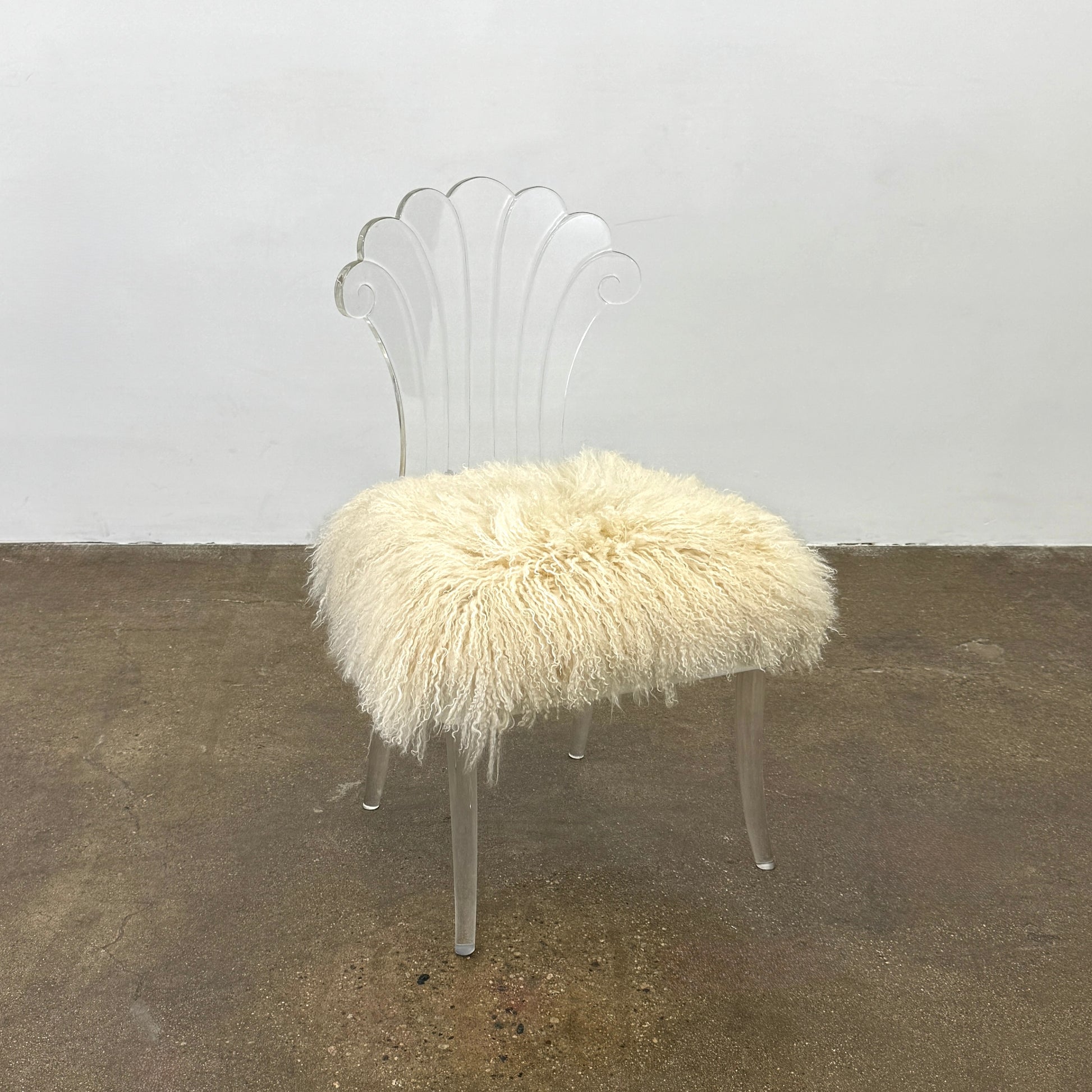 Two white Vintage Elsie de Wolfe Lucite Chairs with elegant fan-shaped backs and plush beige sheepskin seats are displayed against a plain white background.