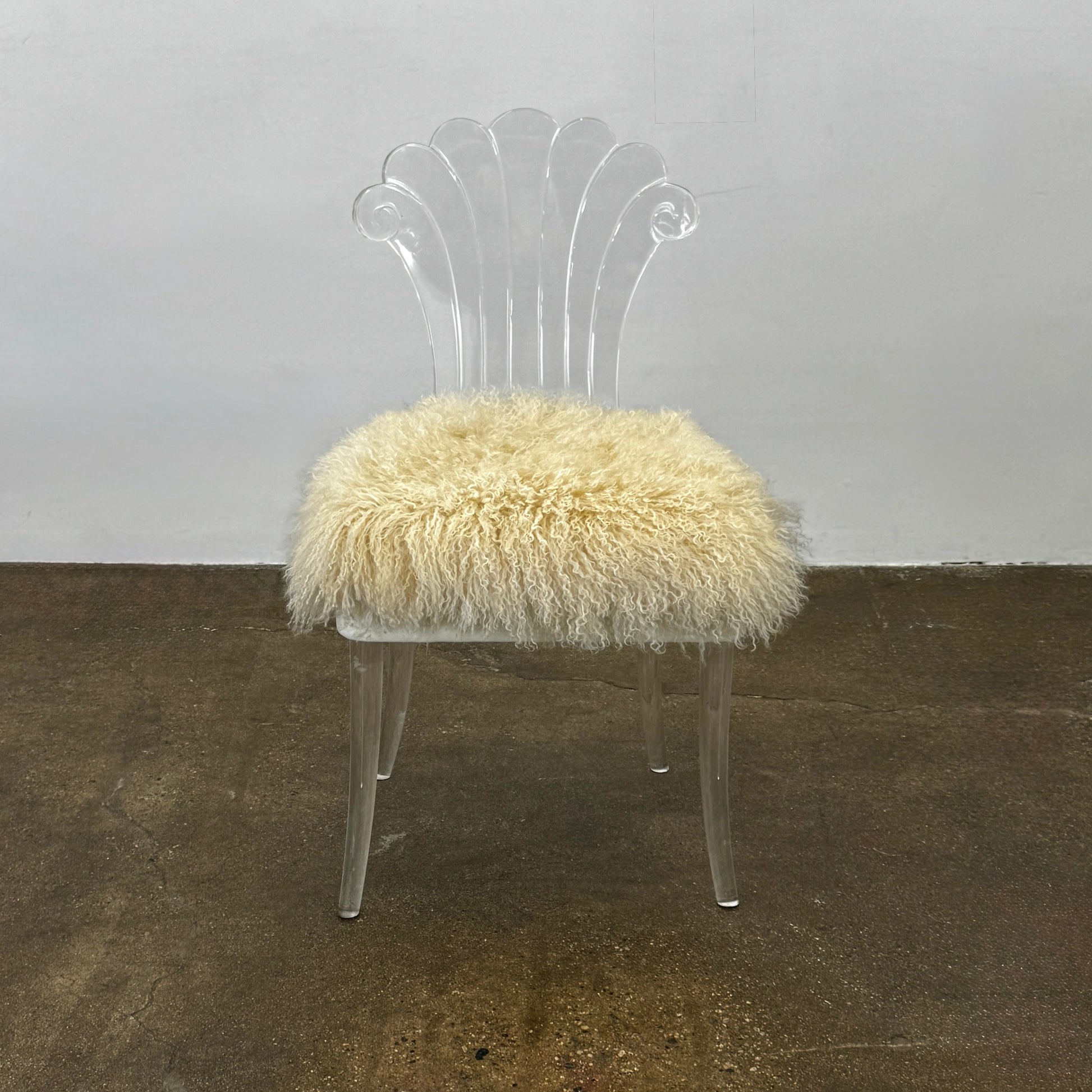 Two white Vintage Elsie de Wolfe Lucite Chairs with elegant fan-shaped backs and plush beige sheepskin seats are displayed against a plain white background.