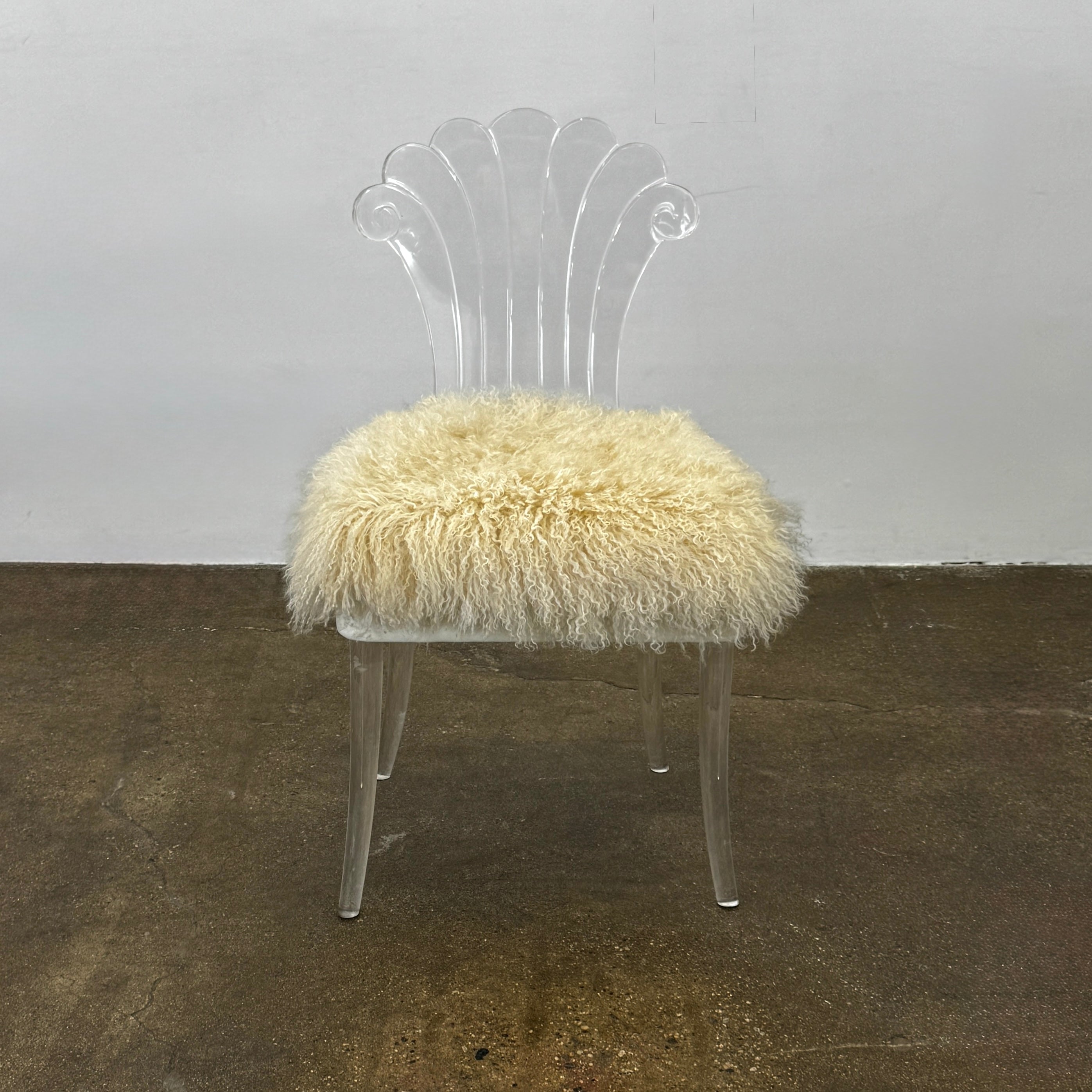 Two white Vintage Elsie de Wolfe Lucite Chairs with elegant fan-shaped backs and plush beige sheepskin seats are displayed against a plain white background.