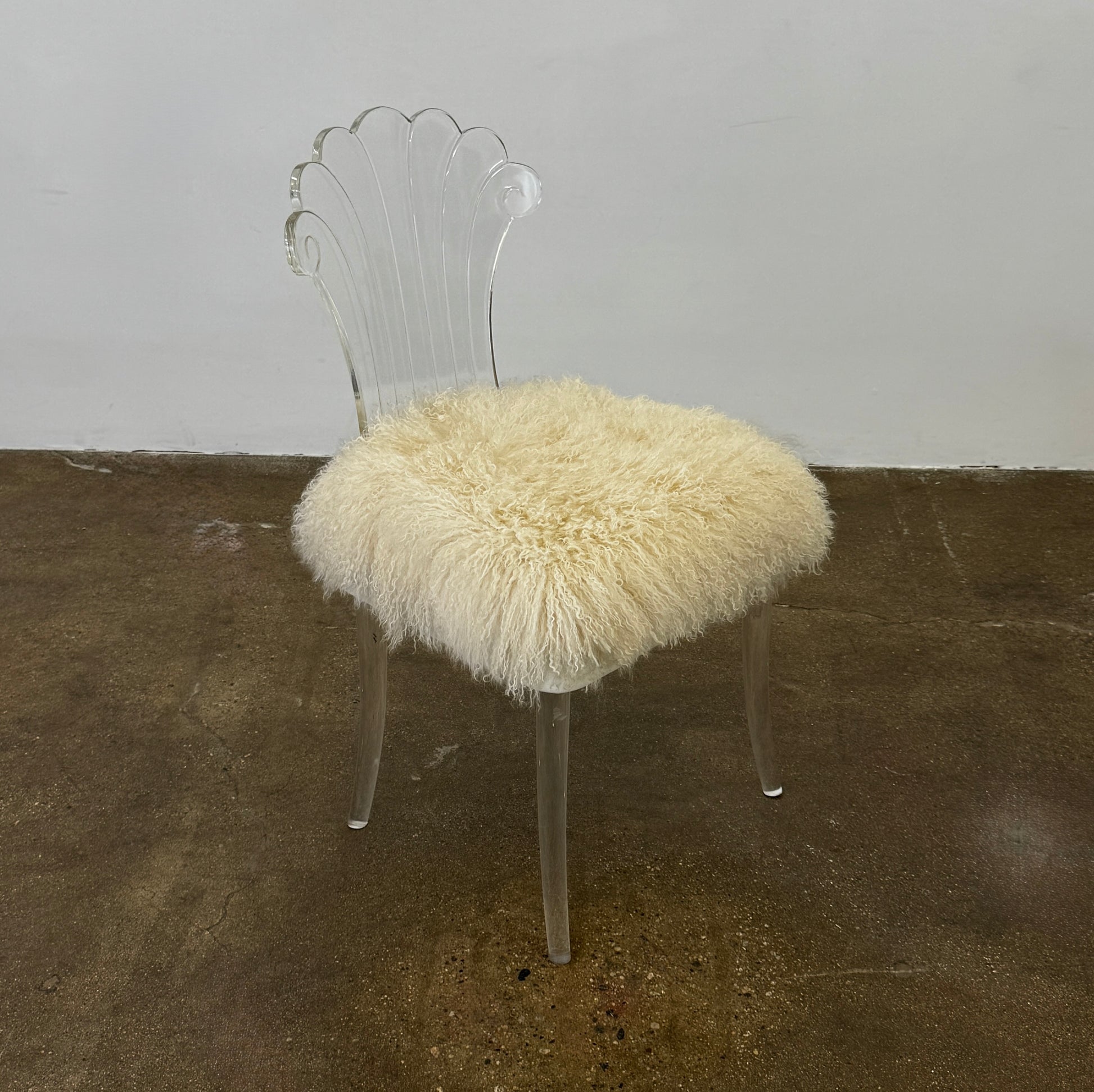 Two white Vintage Elsie de Wolfe Lucite Chairs with elegant fan-shaped backs and plush beige sheepskin seats are displayed against a plain white background.