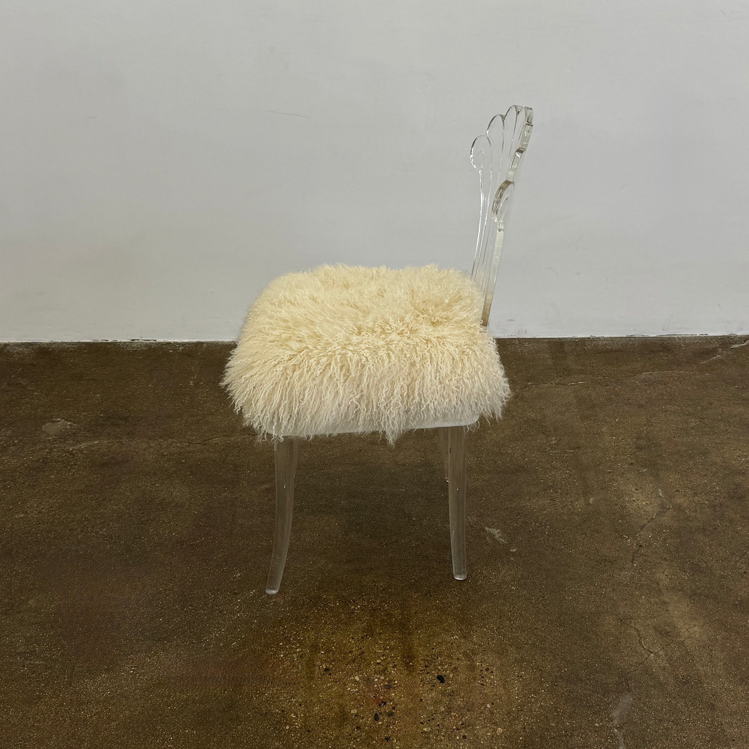 Two white Vintage Elsie de Wolfe Lucite Chairs with elegant fan-shaped backs and plush beige sheepskin seats are displayed against a plain white background.