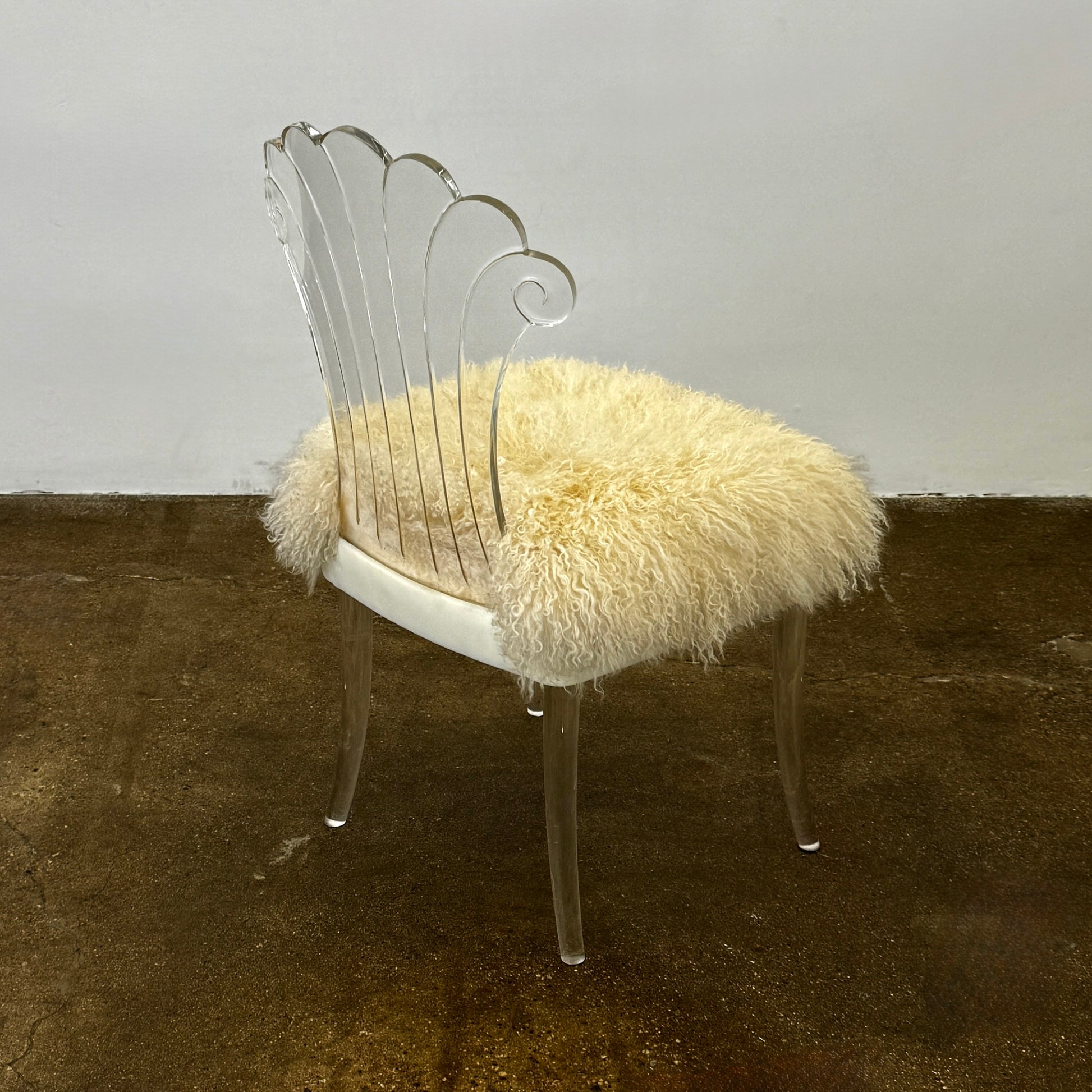 Two white Vintage Elsie de Wolfe Lucite Chairs with elegant fan-shaped backs and plush beige sheepskin seats are displayed against a plain white background.