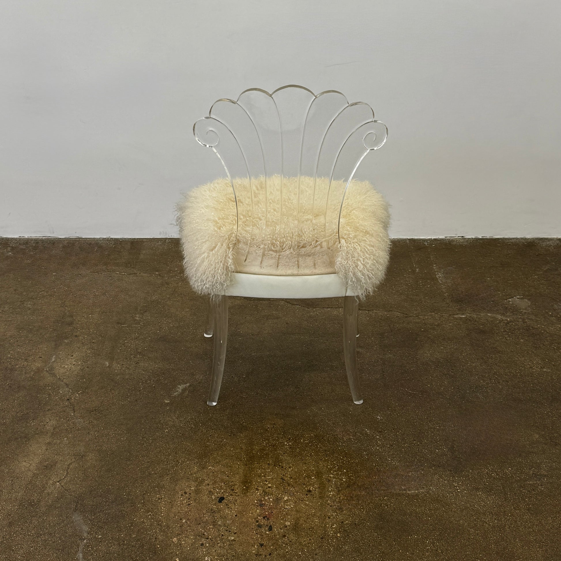 Two white Vintage Elsie de Wolfe Lucite Chairs with elegant fan-shaped backs and plush beige sheepskin seats are displayed against a plain white background.