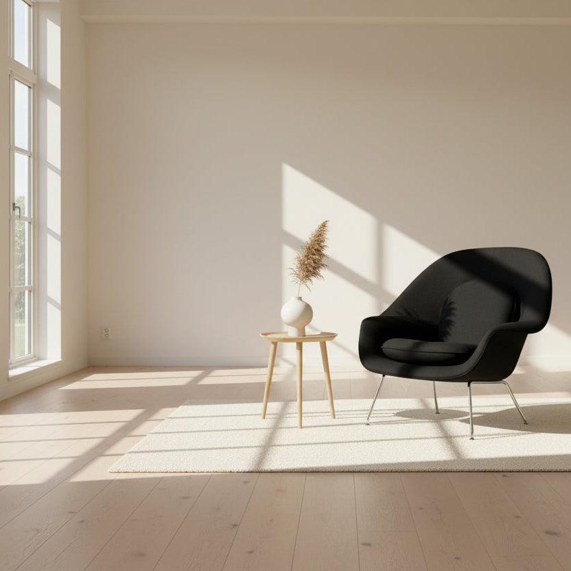 The Knoll Womb Chair by Knoll features a black curved seat, padded cushion, and metal legs, drawing inspiration from midcentury modern design and the iconic Saarinen style. Shown here against a plain white background.