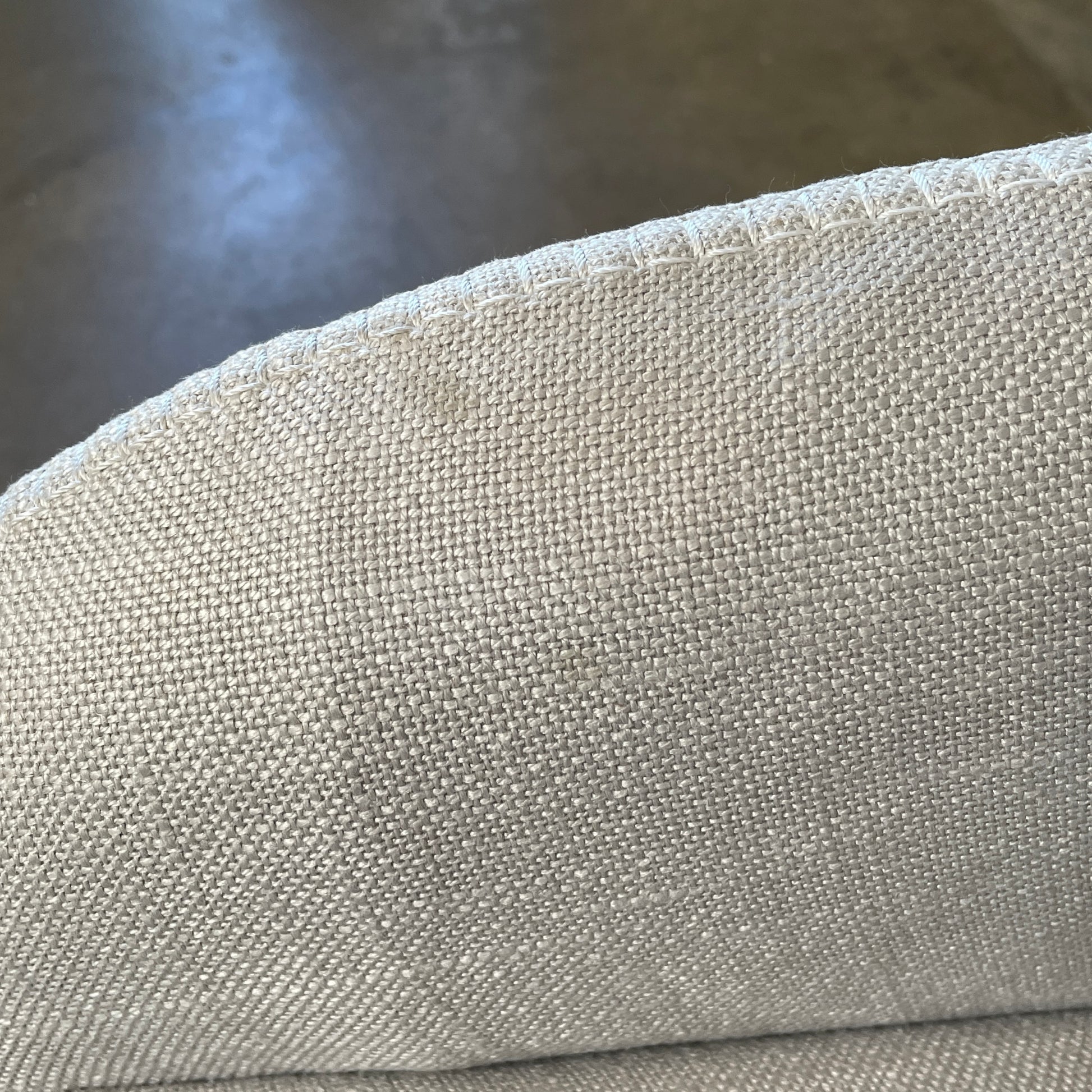 The beige upholstered chair, similar to the Maxalto Agathos Swivel Lounge Chairs, showcases a high back and a skirted bottom against a plain background.