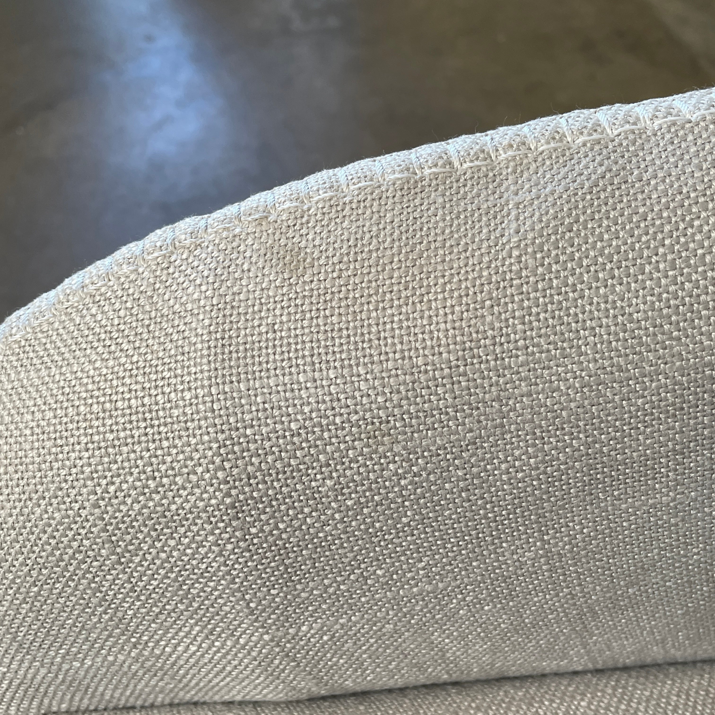 The beige upholstered chair, similar to the Maxalto Agathos Swivel Lounge Chairs, showcases a high back and a skirted bottom against a plain background.