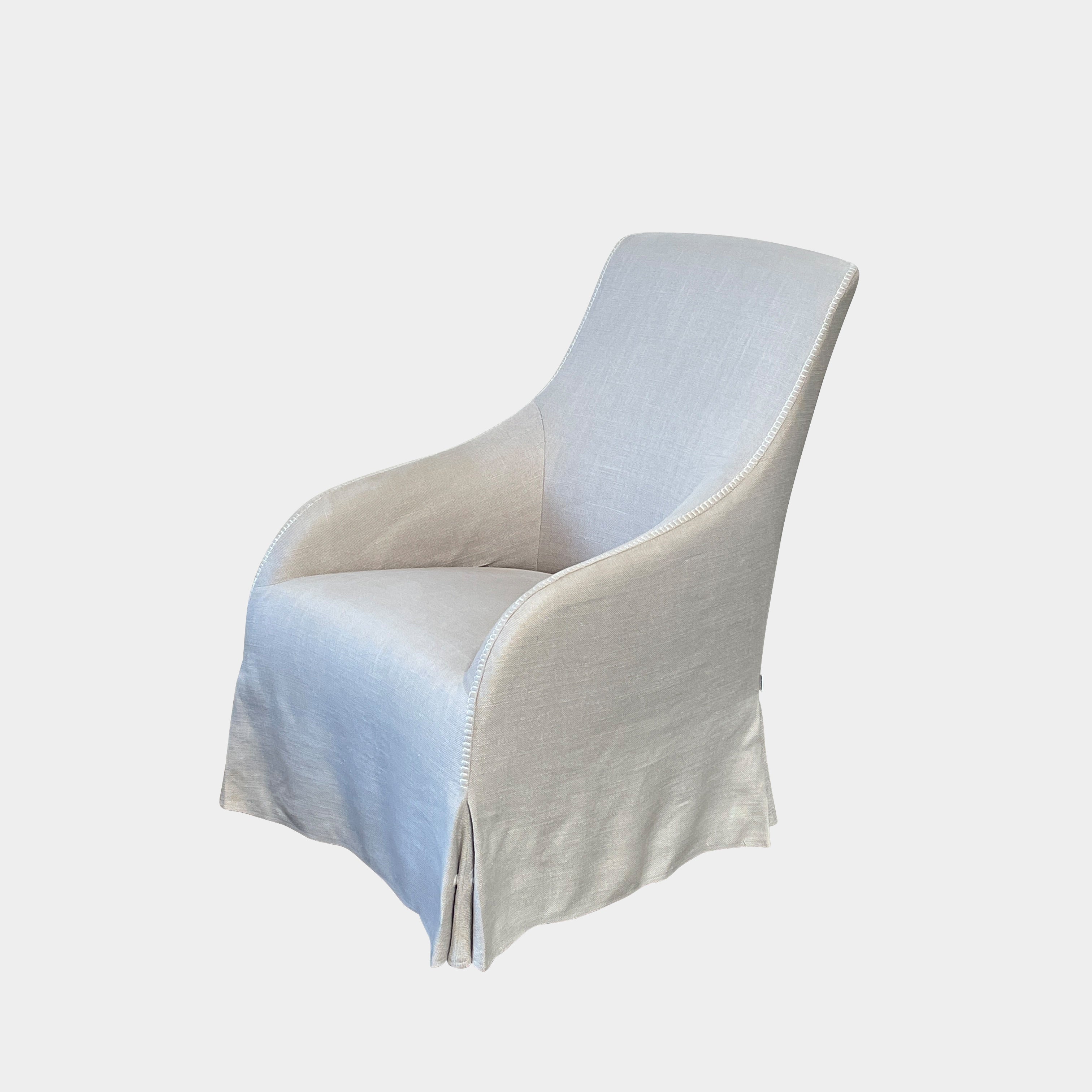 The beige upholstered chair, similar to the Maxalto Agathos Swivel Lounge Chairs, showcases a high back and a skirted bottom against a plain background.