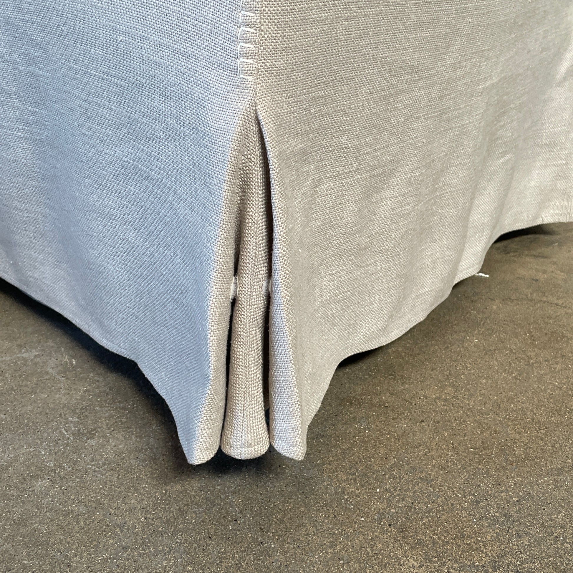 The beige upholstered chair, similar to the Maxalto Agathos Swivel Lounge Chairs, showcases a high back and a skirted bottom against a plain background.