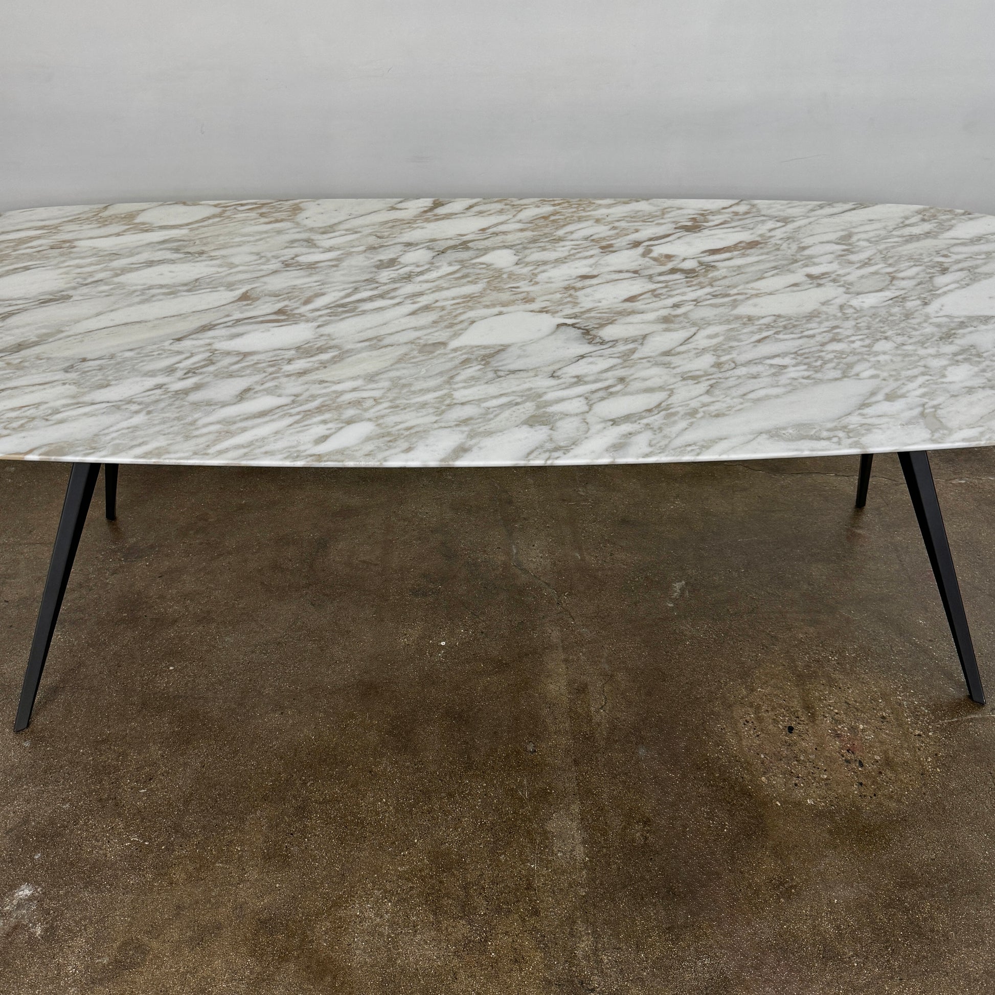 The Flexform Zefiro Dining Table by Flexform features a rectangular Calacatta Gold marble top with rounded edges and four black angled legs, shown on a plain white background.