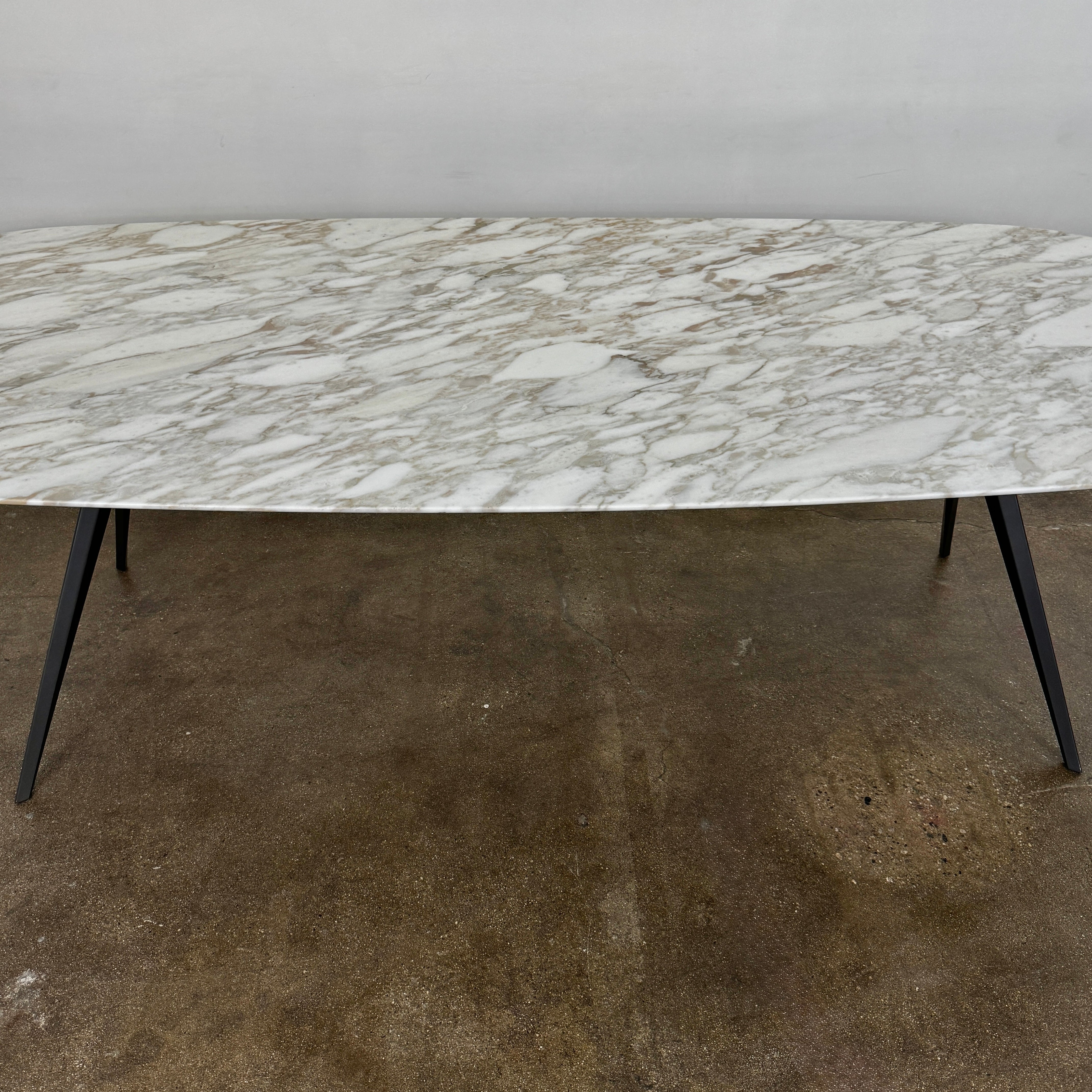 The Flexform Zefiro Dining Table by Flexform features a rectangular Calacatta Gold marble top with rounded edges and four black angled legs, shown on a plain white background.