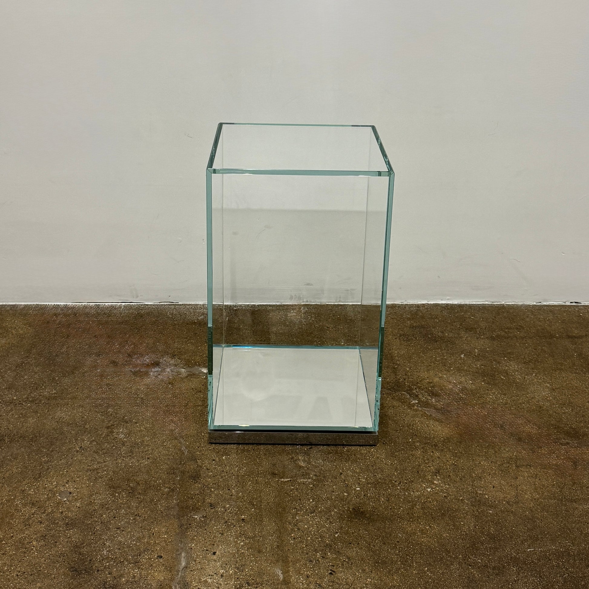 A clear rectangular glass display case with a metal base, inspired by the Cassina Volage side table Philippe Starck from Cassina, shown against a plain white background.