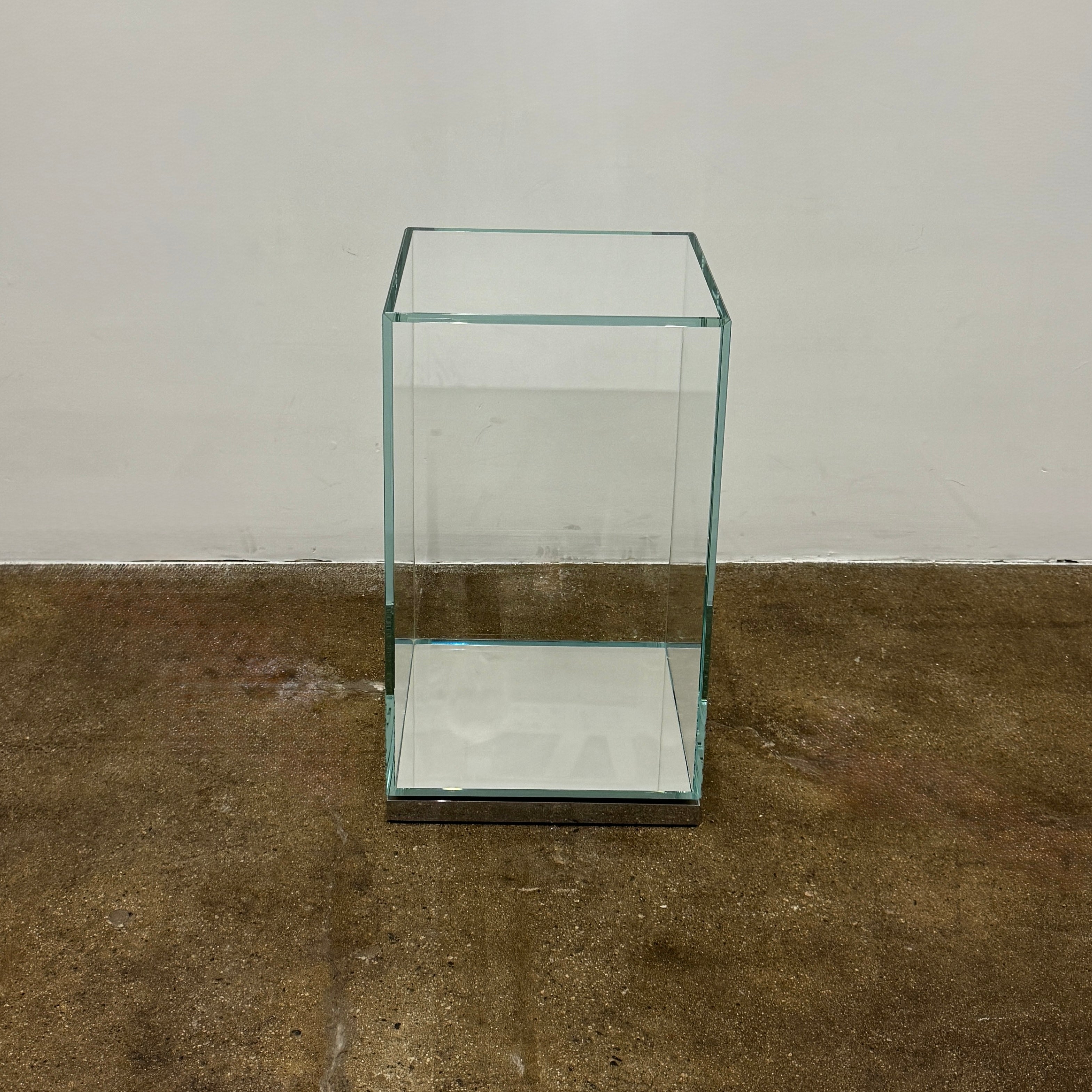 A clear rectangular glass display case with a metal base, inspired by the Cassina Volage side table Philippe Starck from Cassina, shown against a plain white background.