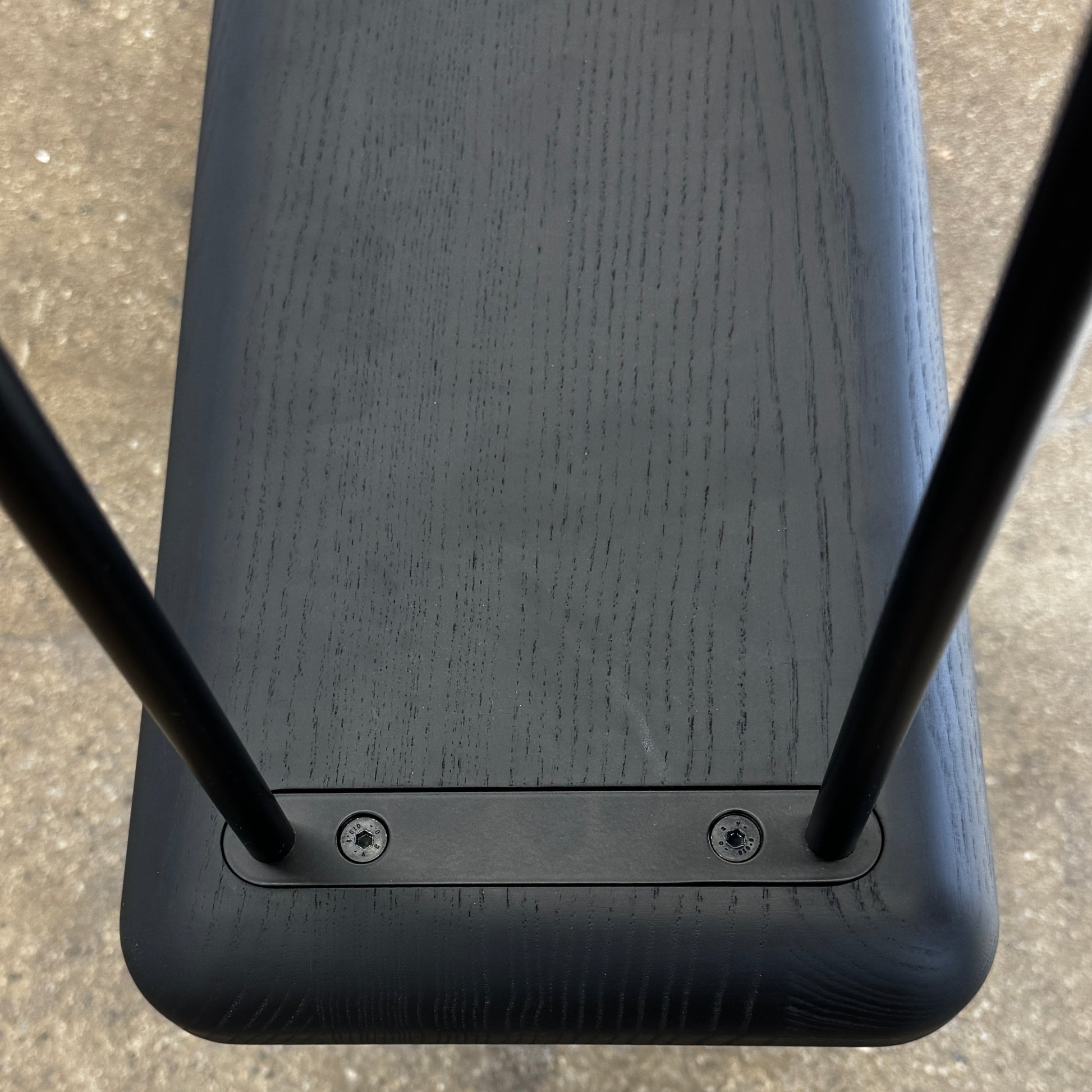 A minimalist black bench with a rectangular seat and slim metal legs echoes the elegant design of the Cassina Torei Occasional Table in Black Ash by Cassina, displayed against a plain white background.