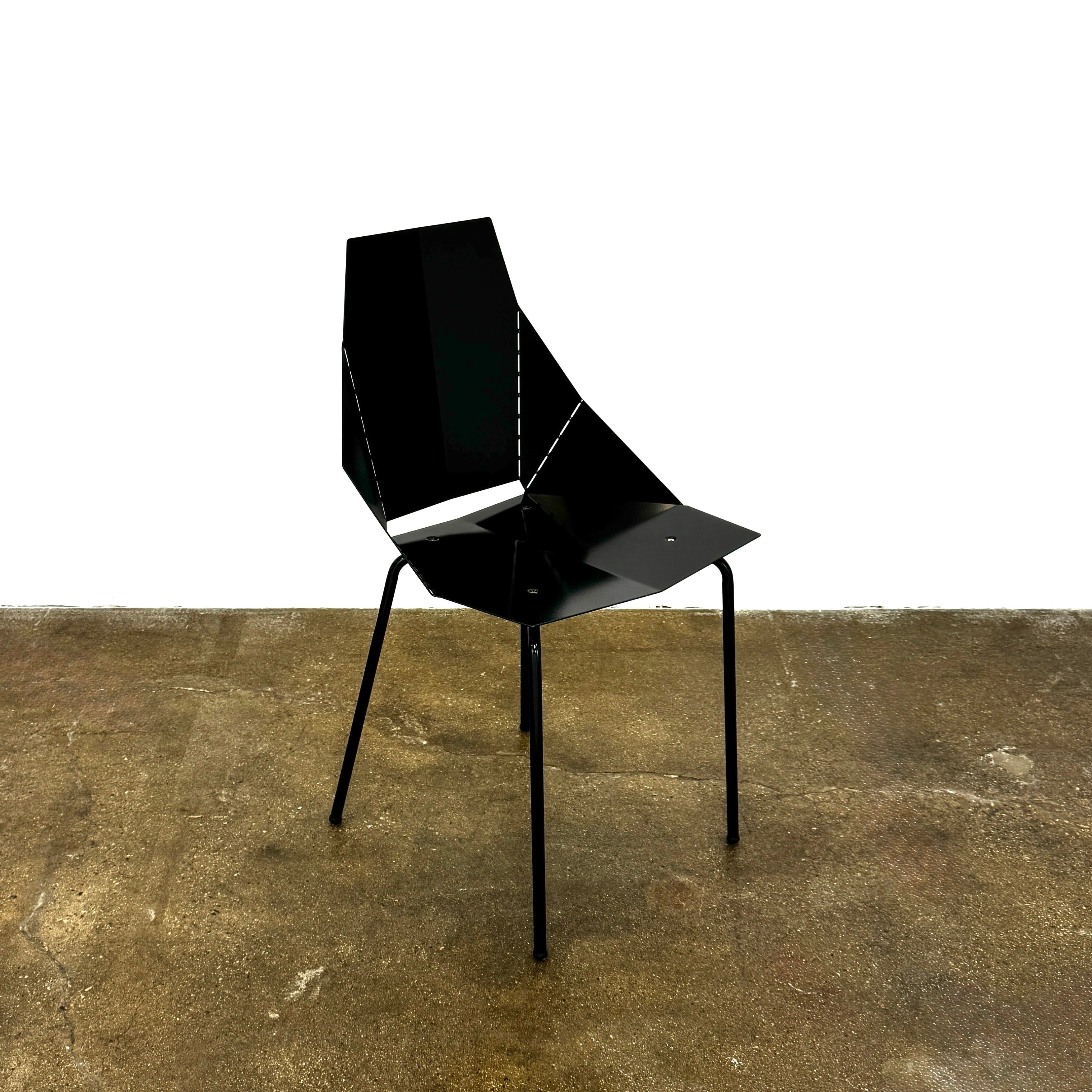 The Blu Dot “Real Good Chair” by Blu Dot is a black, angular steel chair with four metal legs and a powder-coated finish, shown against a plain white background.