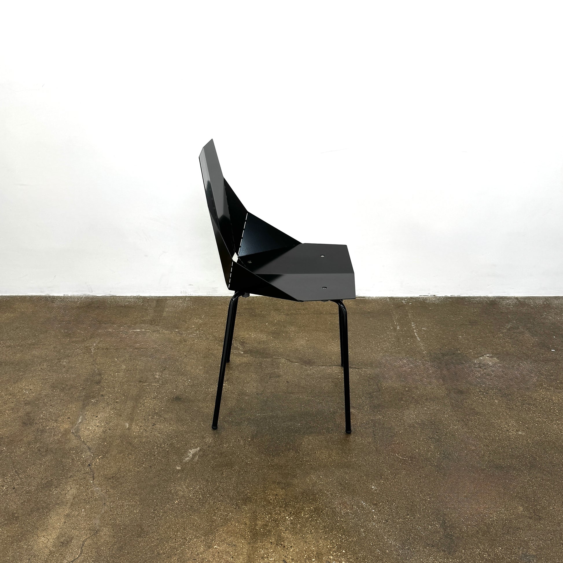 The Blu Dot “Real Good Chair” by Blu Dot is a black, angular steel chair with four metal legs and a powder-coated finish, shown against a plain white background.