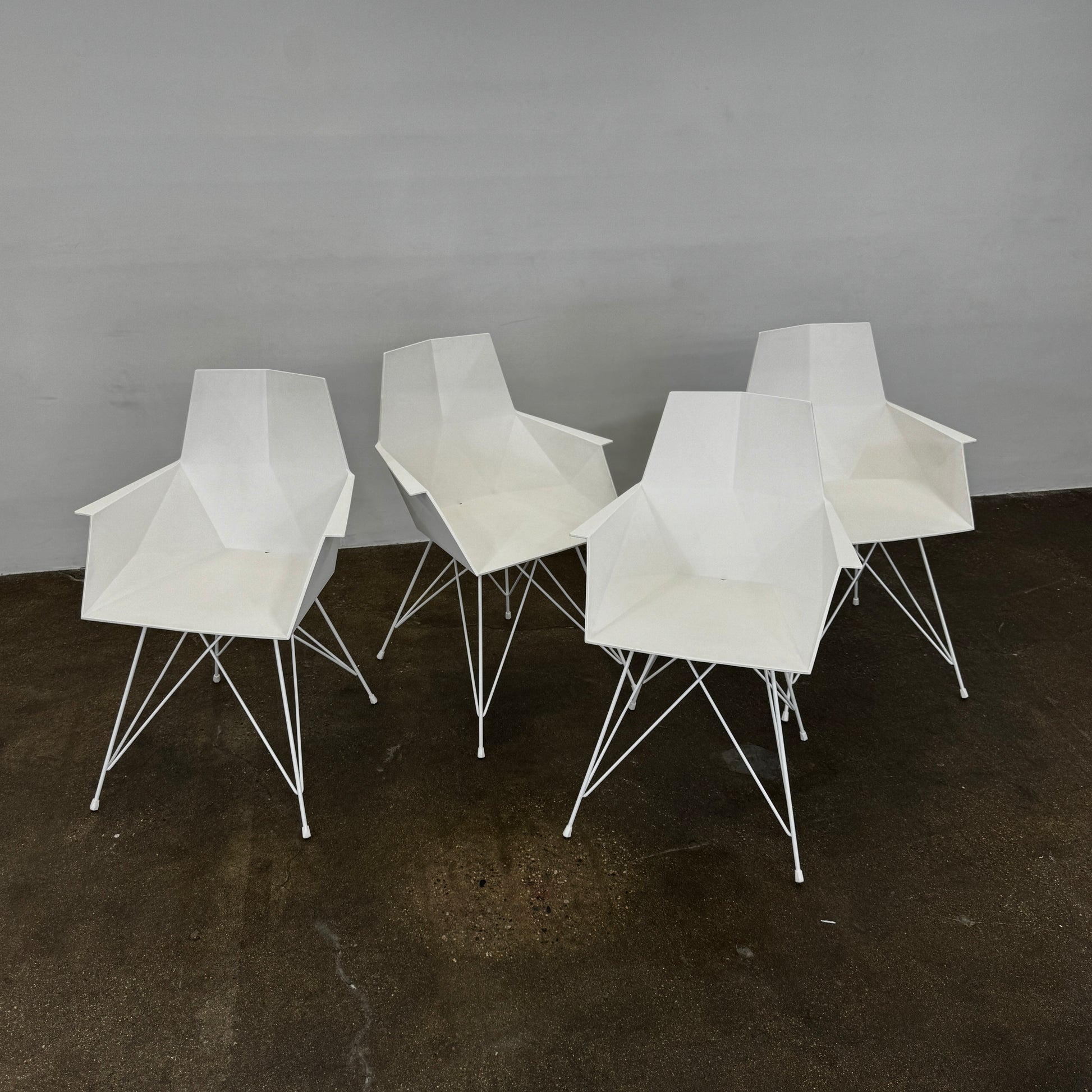 Four Vondom Faz Armchairs with steel bases, designed by Vondom, are arranged in two rows against a plain white background, highlighting their modern geometric style. Set includes four chairs.