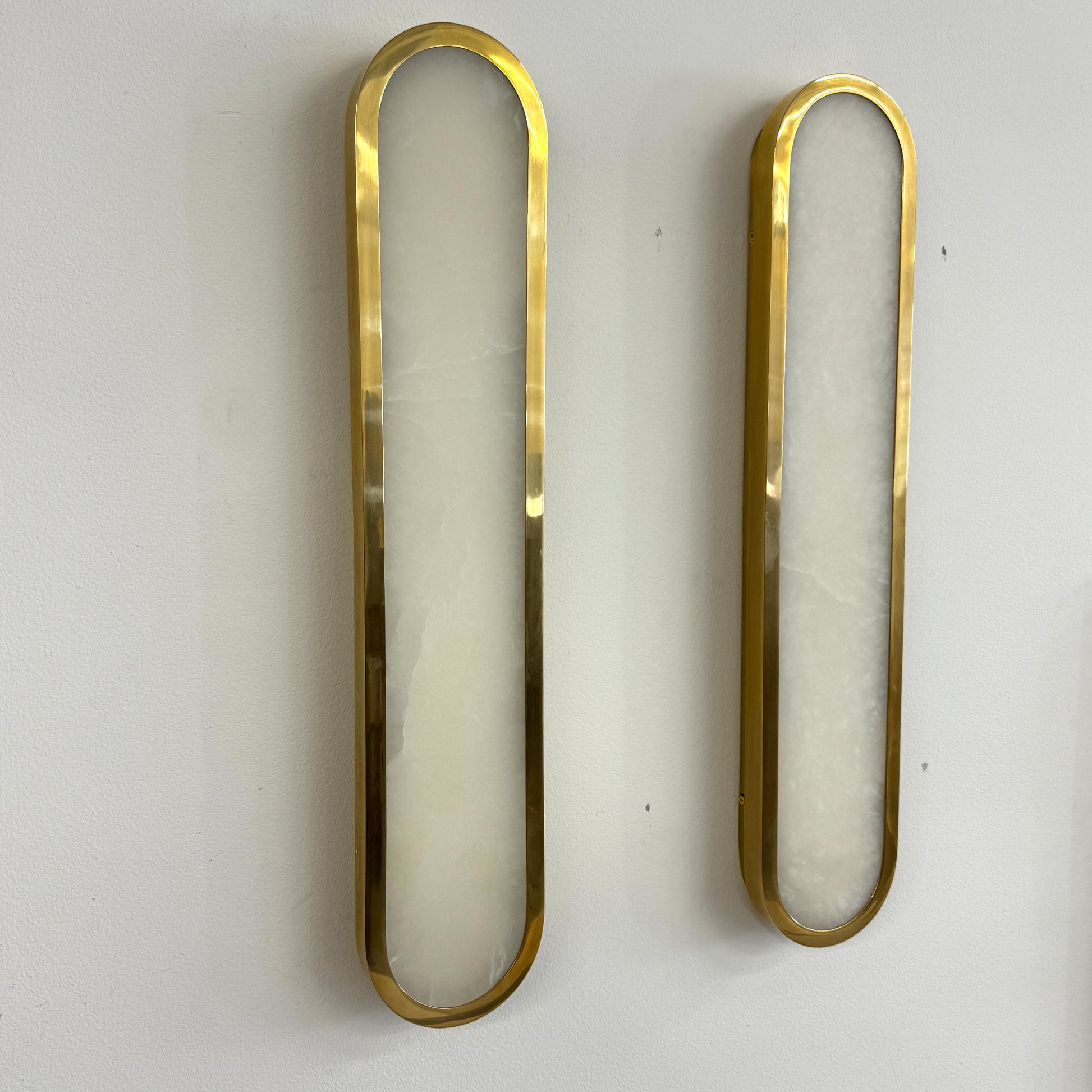 A set of two Hudson Valley Lighting Manhasset LED Wall Sconces, featuring gold frames and white alabaster diffusers, displayed side by side on a plain background.