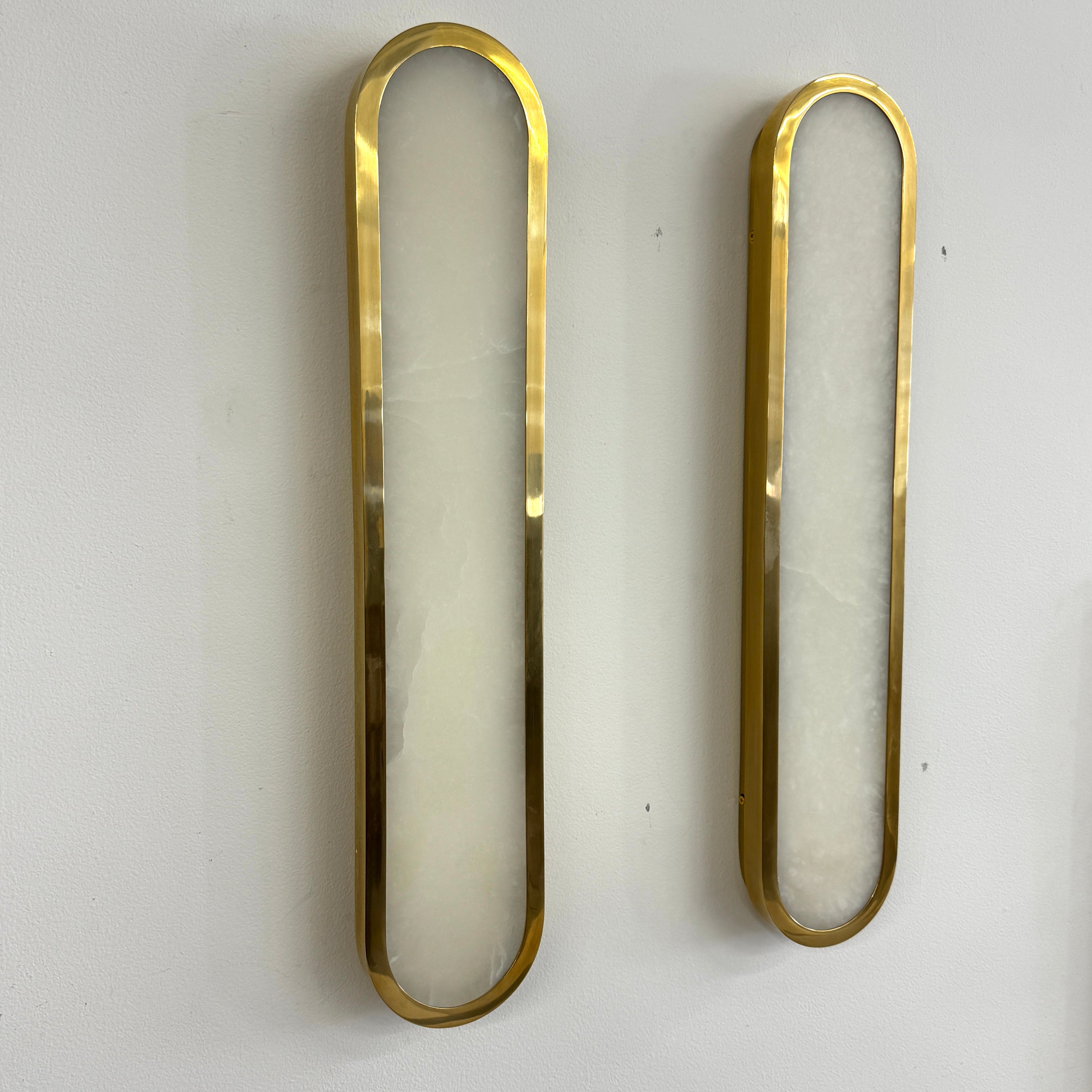 A set of two Hudson Valley Lighting Manhasset LED Wall Sconces, featuring gold frames and white alabaster diffusers, displayed side by side on a plain background.
