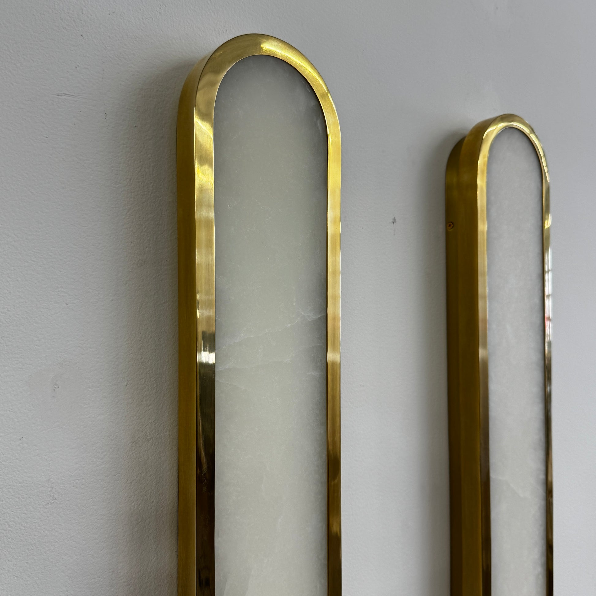 A set of two Hudson Valley Lighting Manhasset LED Wall Sconces, featuring gold frames and white alabaster diffusers, displayed side by side on a plain background.