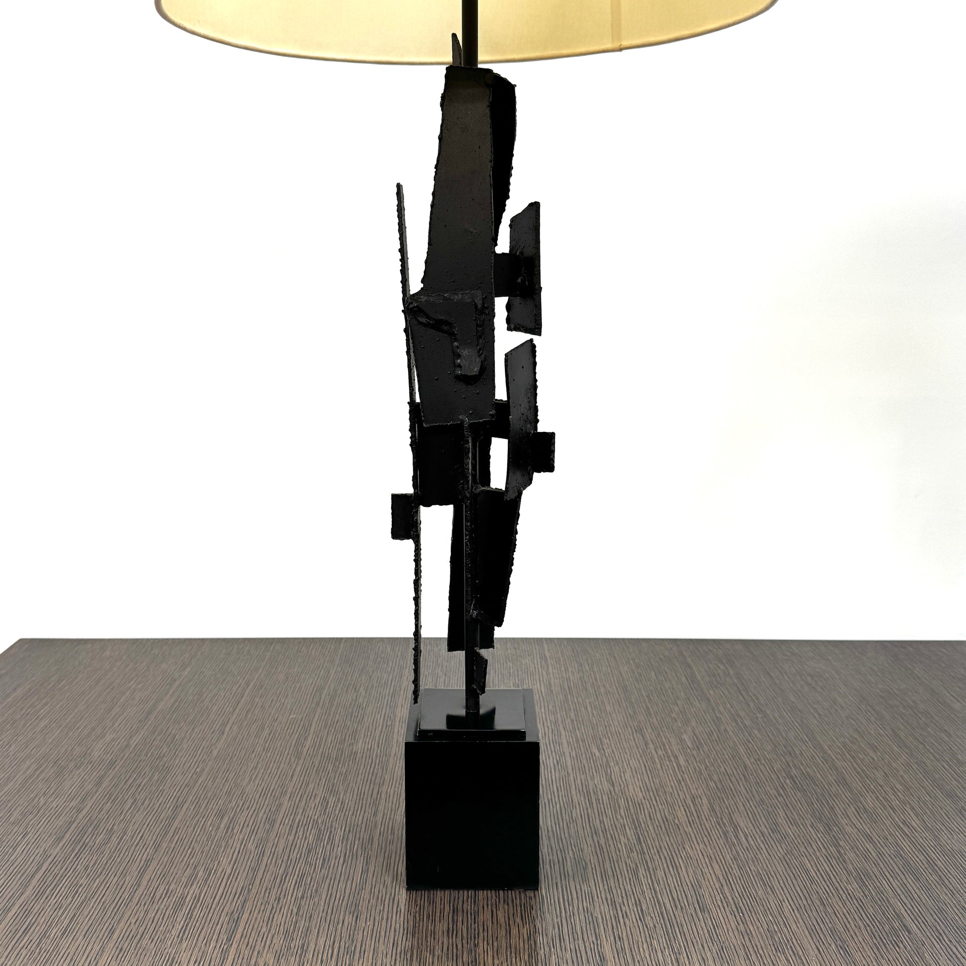 A pair of Vintage Richard Barr Iron Brutalist table lamps for Laurel Lamp Co., featuring abstract black metal bases and cylindrical white shades, set against a plain white background.