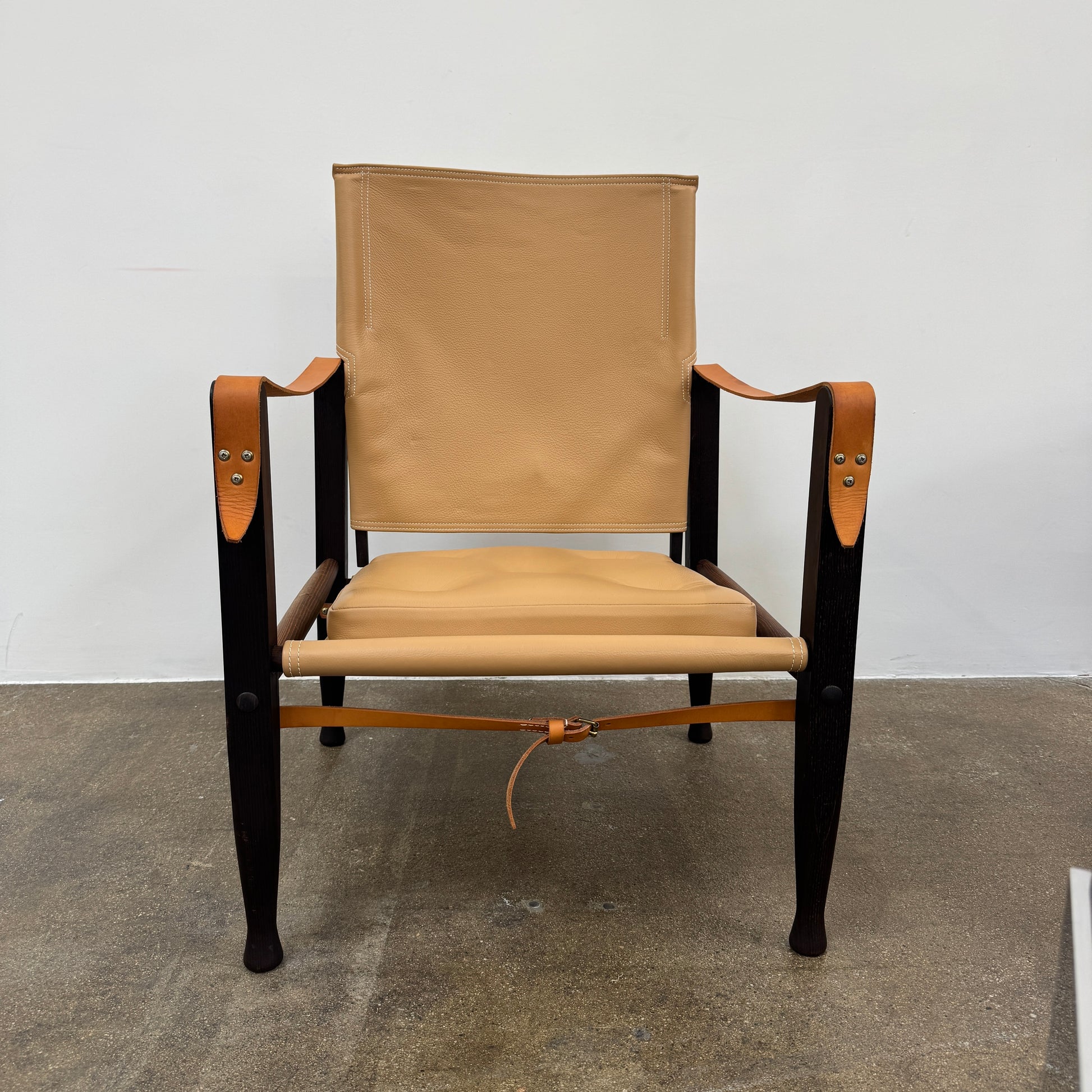 The Carl Hansen & Son KK47000 Safari Lounge Chair by Kaare Klint features canvas and leather with wooden legs and armrests, shown from the front on a plain white background.