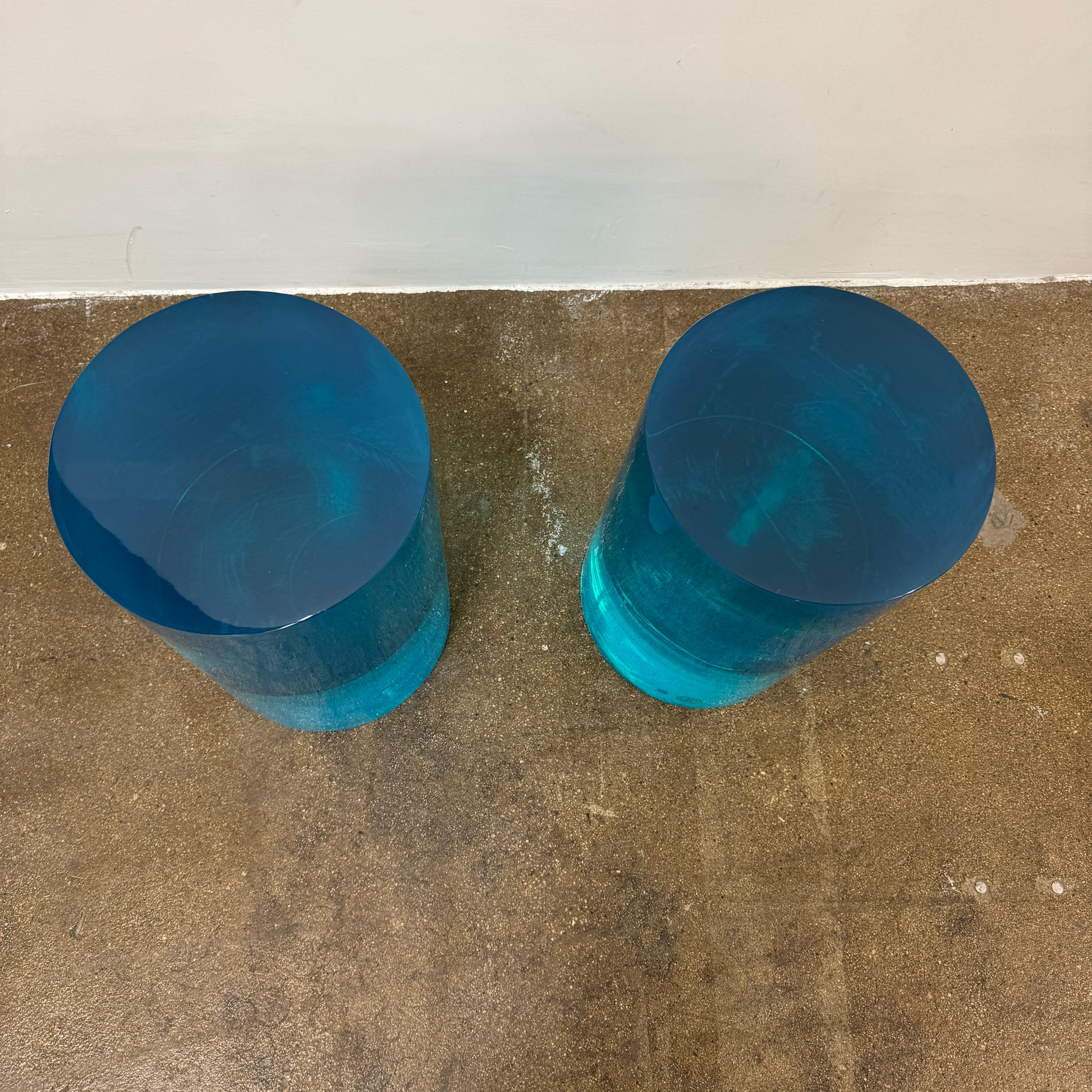 The Jonathan Adler blue acrylic cylindrical table stands upright on a white background, featuring smooth sides and a flat top that evoke the brand’s modern, chic design aesthetic.