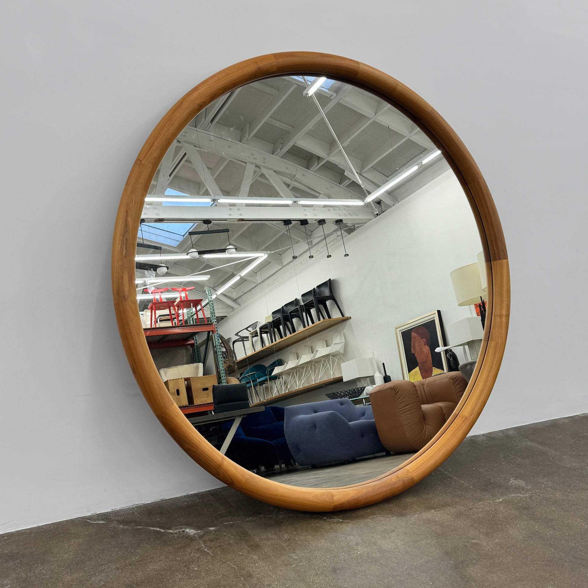 The Porada Giove Mirror with Canaletta Walnut Frame by Porada leans against the wall, beautifully reflecting a modern space and serving as an eye-catching floor mirror centerpiece.