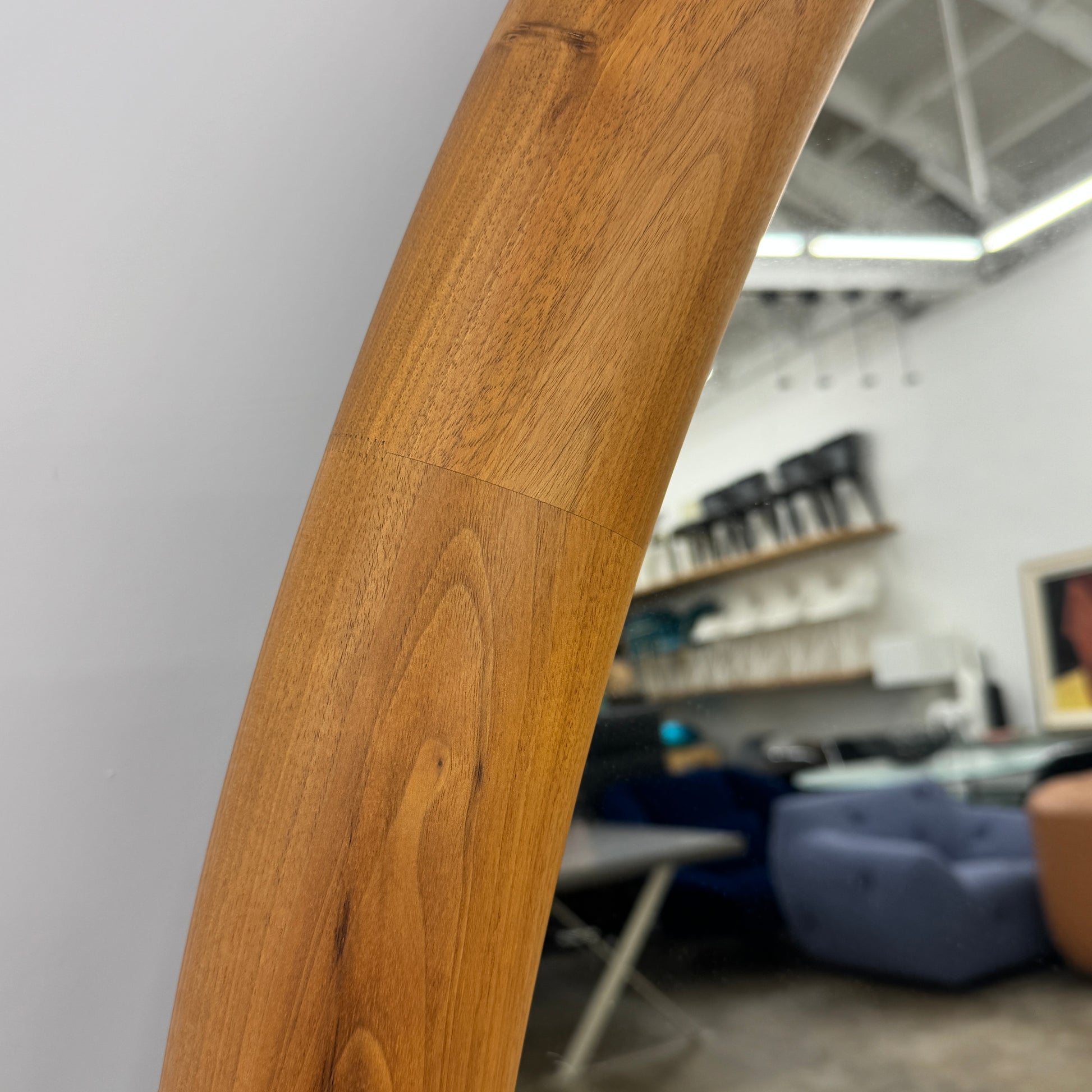 The Porada Giove Mirror with Canaletta Walnut Frame by Porada leans against the wall, beautifully reflecting a modern space and serving as an eye-catching floor mirror centerpiece.