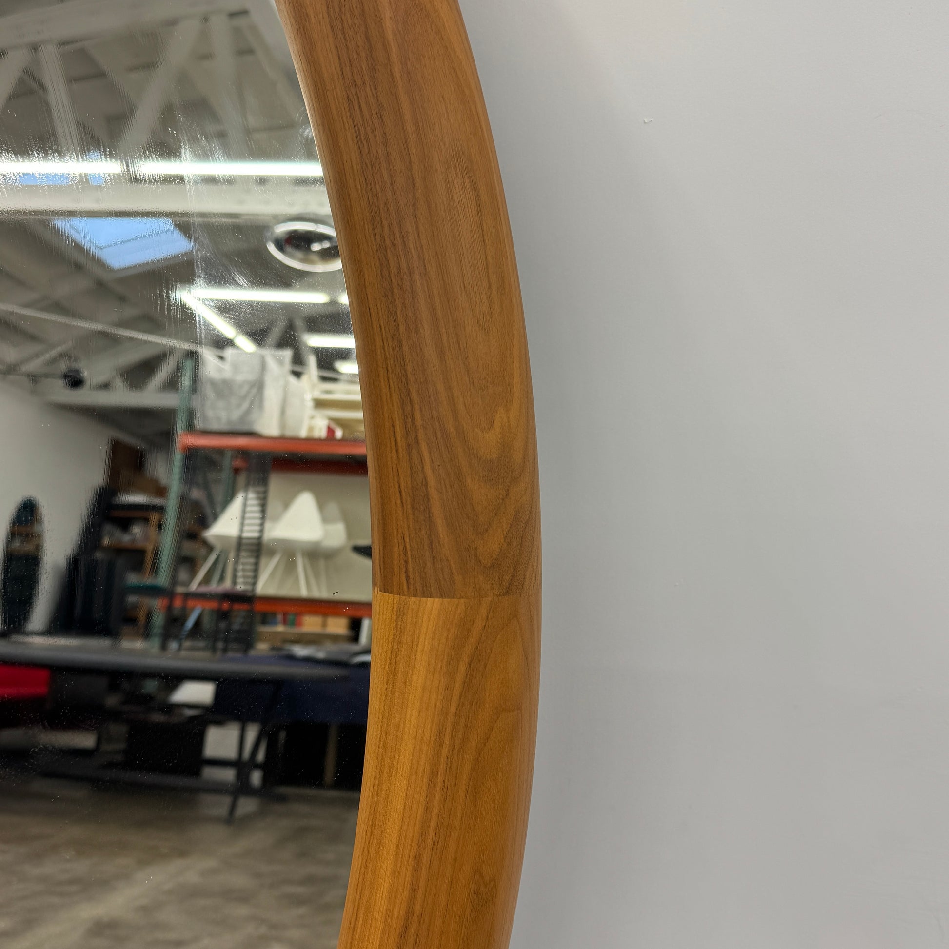 The Porada Giove Mirror with Canaletta Walnut Frame by Porada leans against the wall, beautifully reflecting a modern space and serving as an eye-catching floor mirror centerpiece.