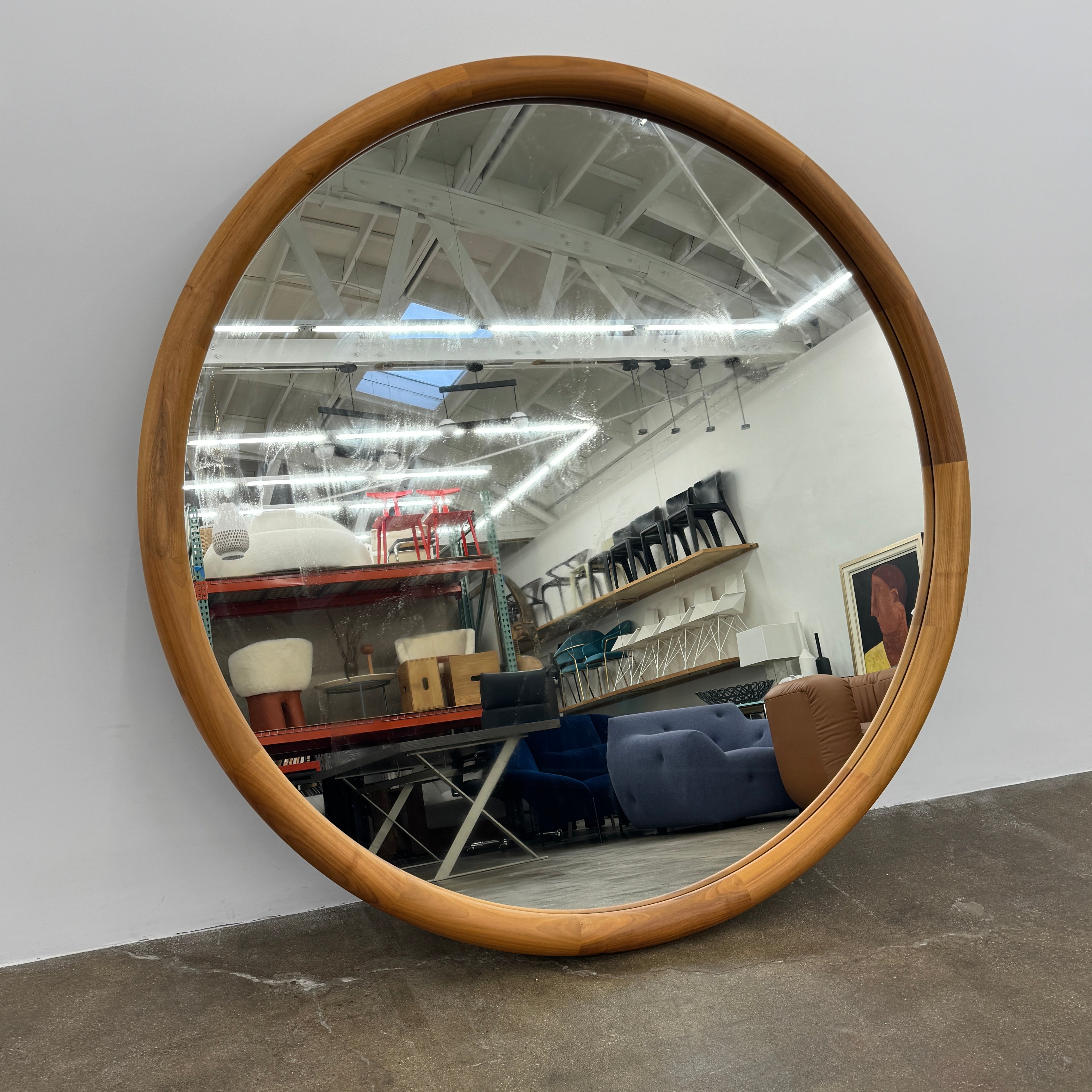 The Porada Giove Mirror with Canaletta Walnut Frame by Porada leans against the wall, beautifully reflecting a modern space and serving as an eye-catching floor mirror centerpiece.