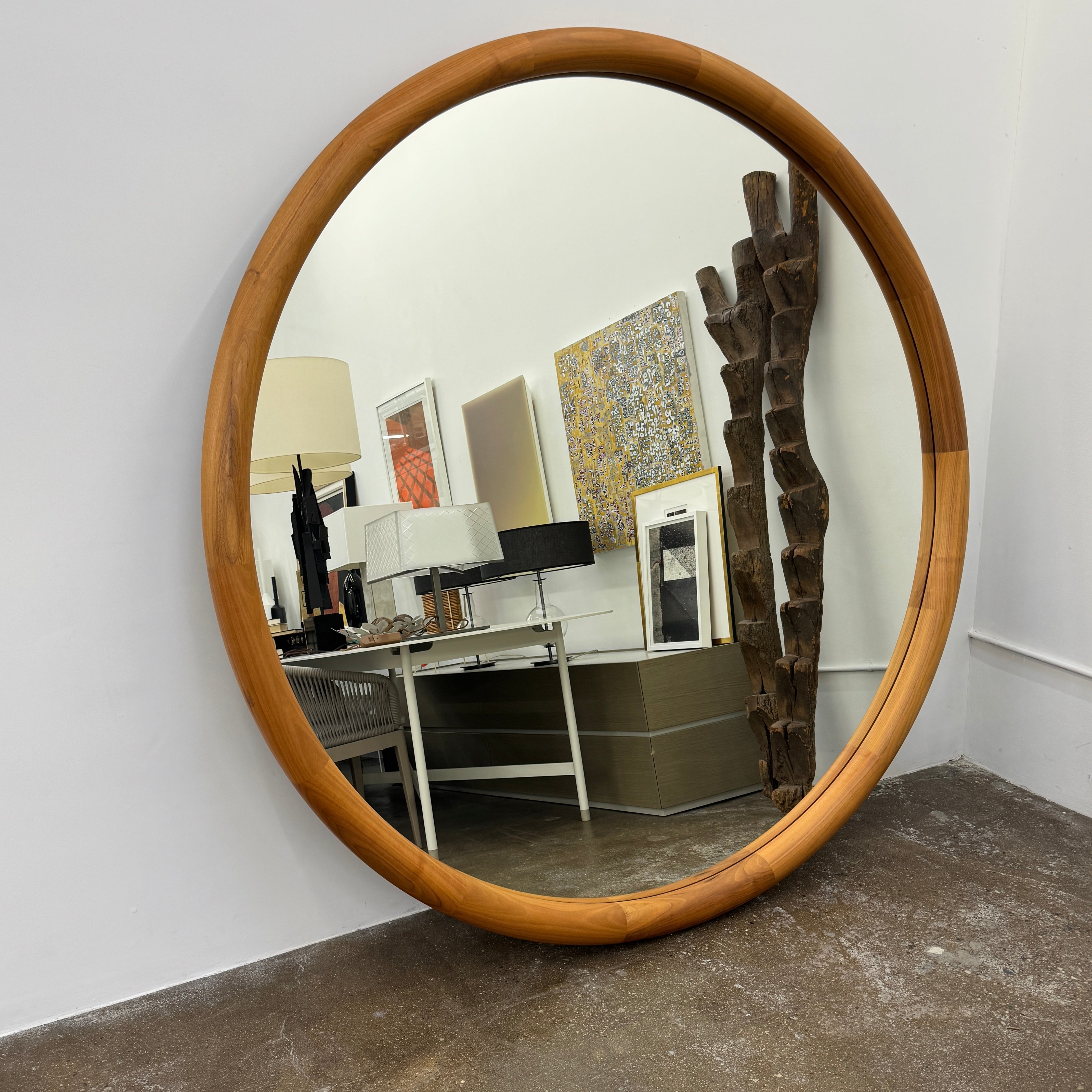 The Porada Giove Mirror with Canaletta Walnut Frame by Porada leans against the wall, beautifully reflecting a modern space and serving as an eye-catching floor mirror centerpiece.