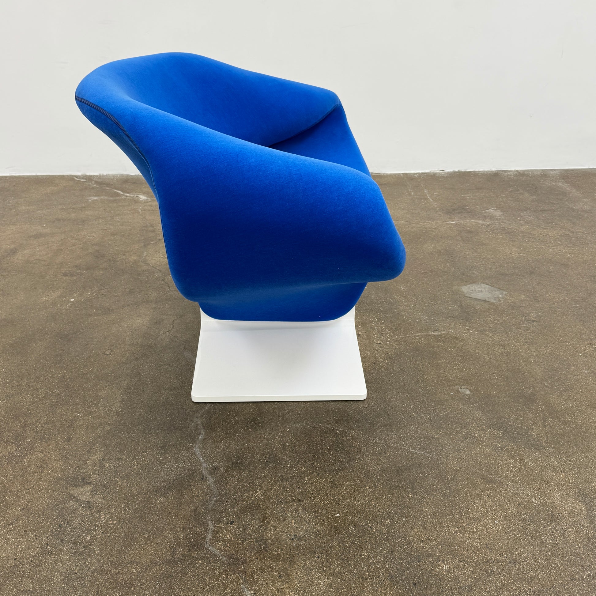 The Artifort Ribbon Lounge Chair & Ottoman by Artifort features a modern blue design with a sculptural curved backrest and split seat on a white base, seen here against a plain white background.