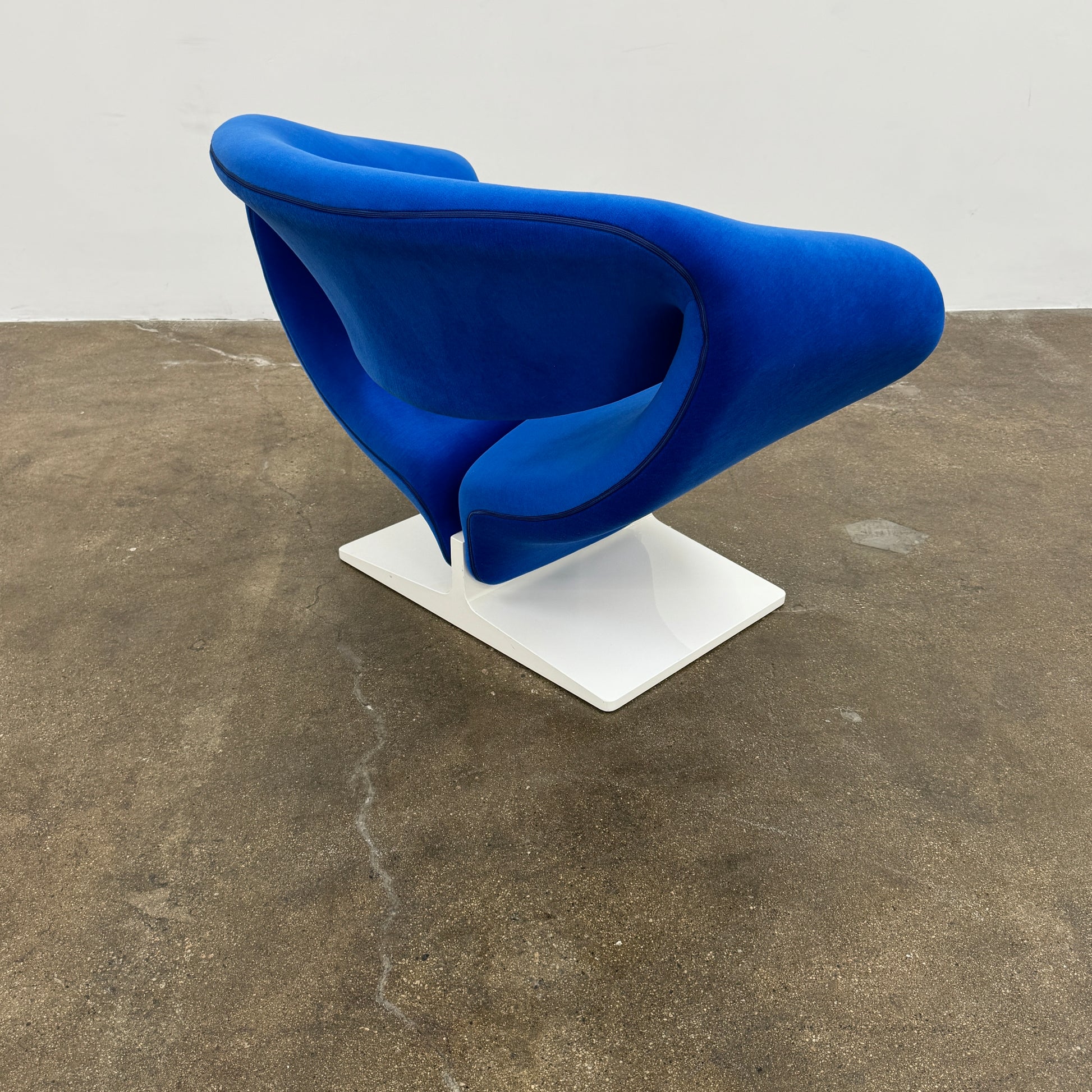 The Artifort Ribbon Lounge Chair & Ottoman by Artifort features a modern blue design with a sculptural curved backrest and split seat on a white base, seen here against a plain white background.