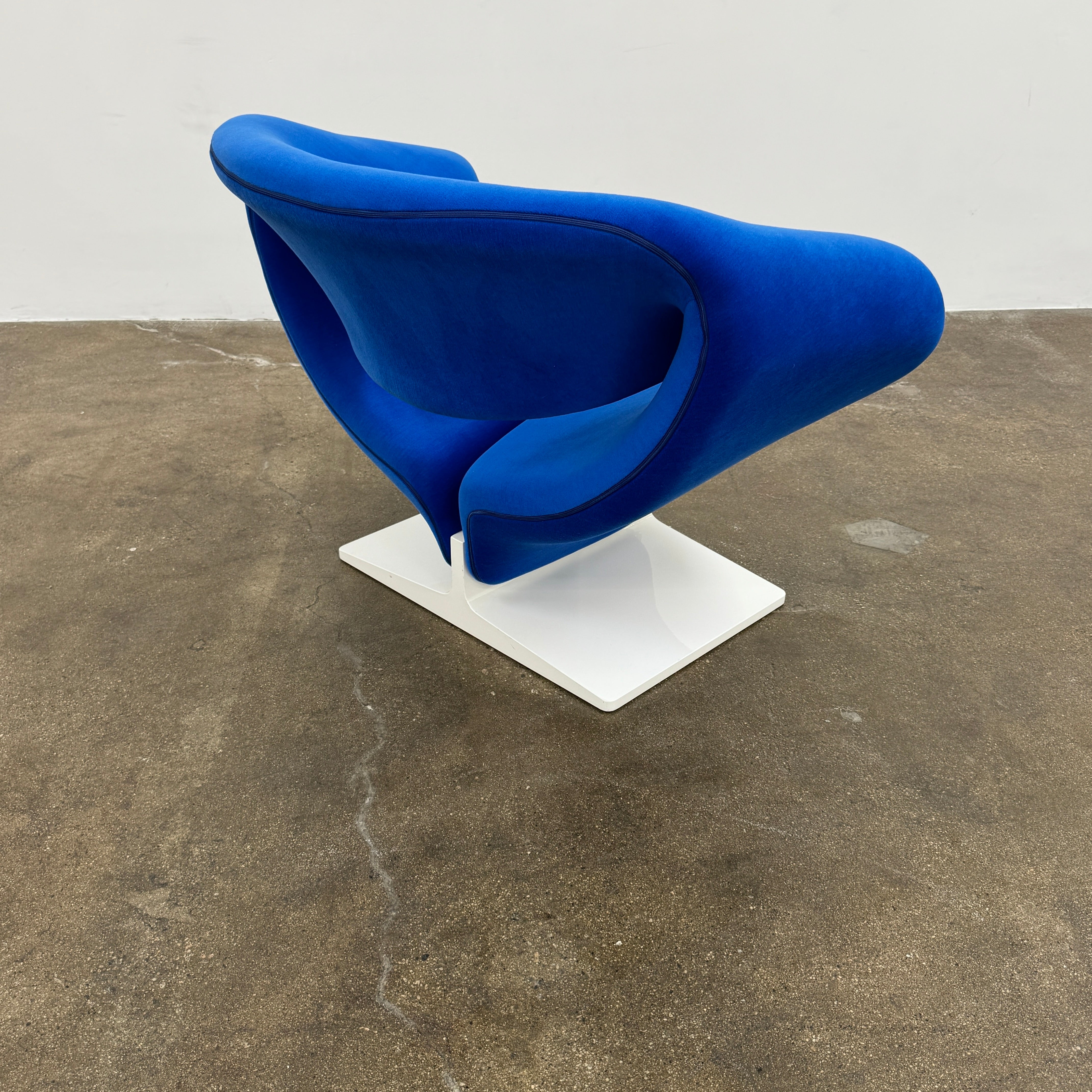 The Artifort Ribbon Lounge Chair & Ottoman by Artifort features a modern blue design with a sculptural curved backrest and split seat on a white base, seen here against a plain white background.