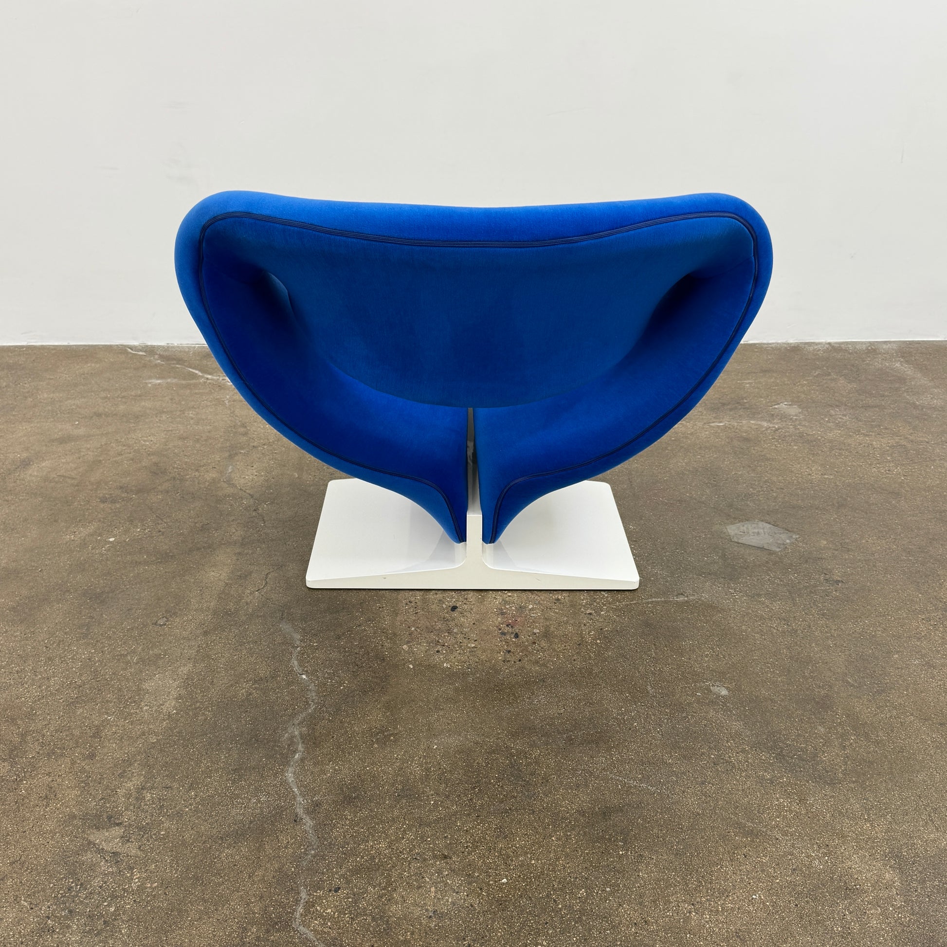 The Artifort Ribbon Lounge Chair & Ottoman by Artifort features a modern blue design with a sculptural curved backrest and split seat on a white base, seen here against a plain white background.