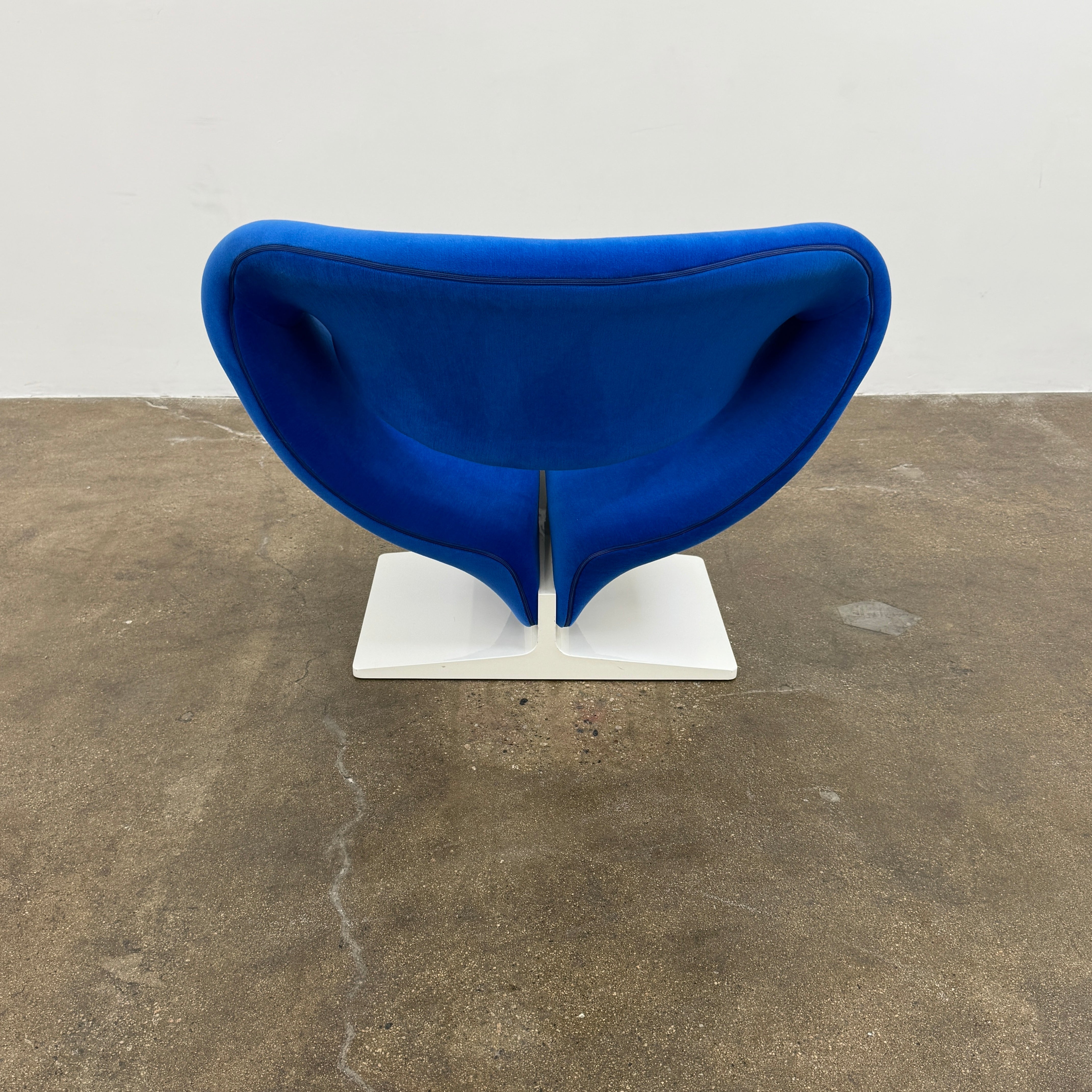 The Artifort Ribbon Lounge Chair & Ottoman by Artifort features a modern blue design with a sculptural curved backrest and split seat on a white base, seen here against a plain white background.