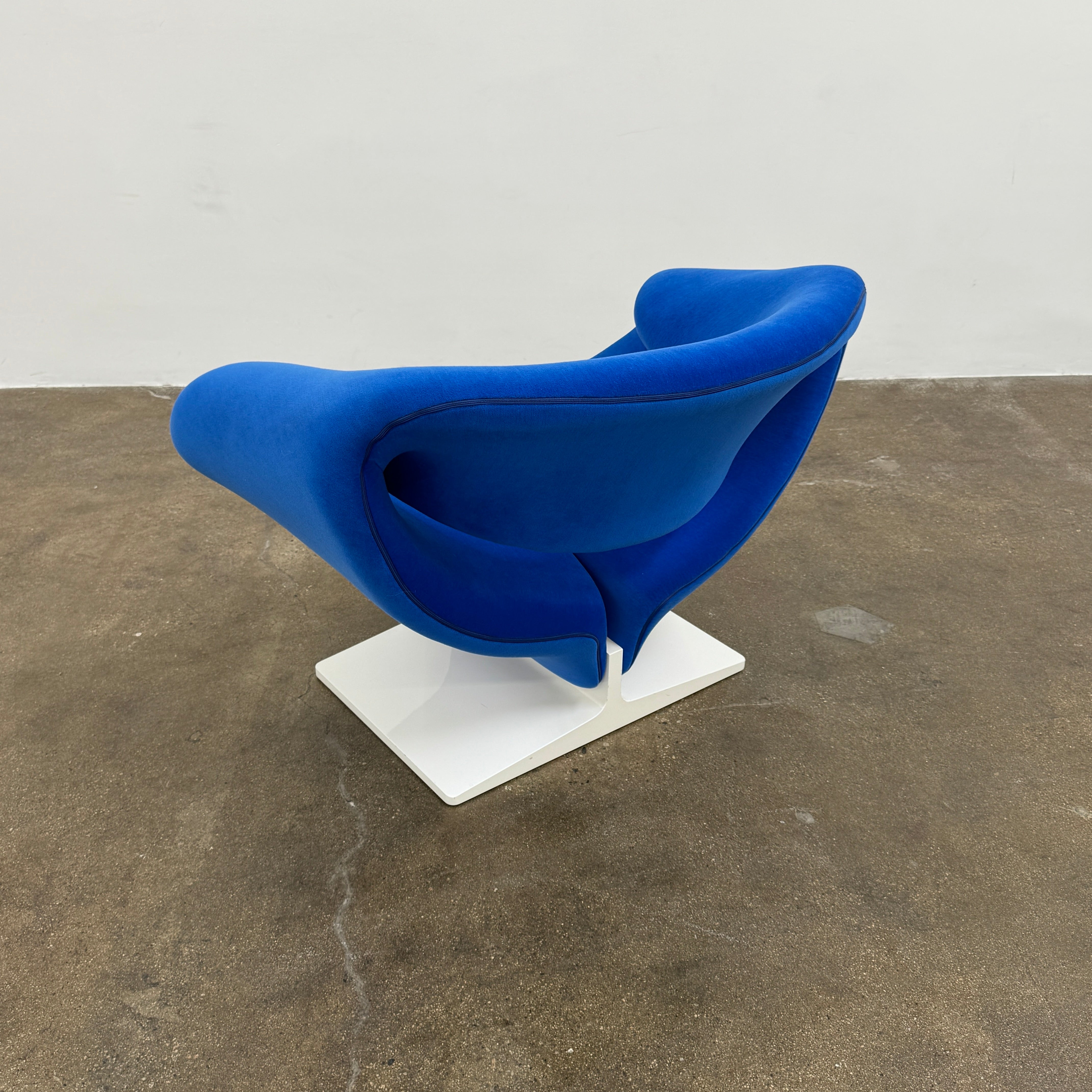 The Artifort Ribbon Lounge Chair & Ottoman by Artifort features a modern blue design with a sculptural curved backrest and split seat on a white base, seen here against a plain white background.