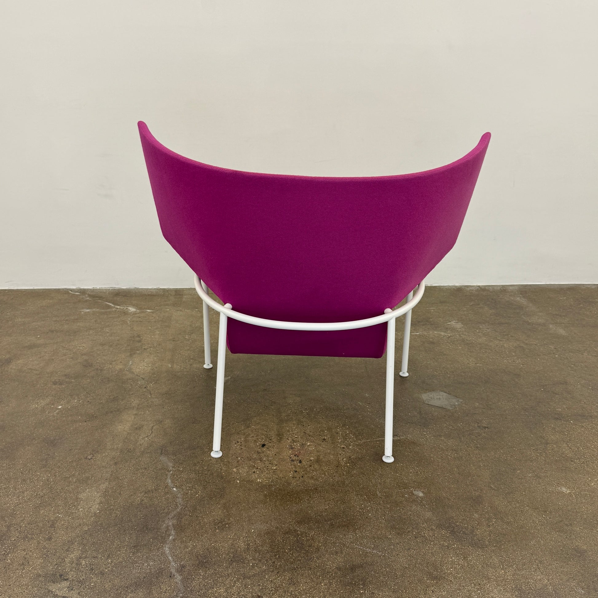 The Cappellini Capo Chair by Cappellini features a modern design with bright magenta upholstery, an angular backrest, and white metal legs, set against a plain white background.