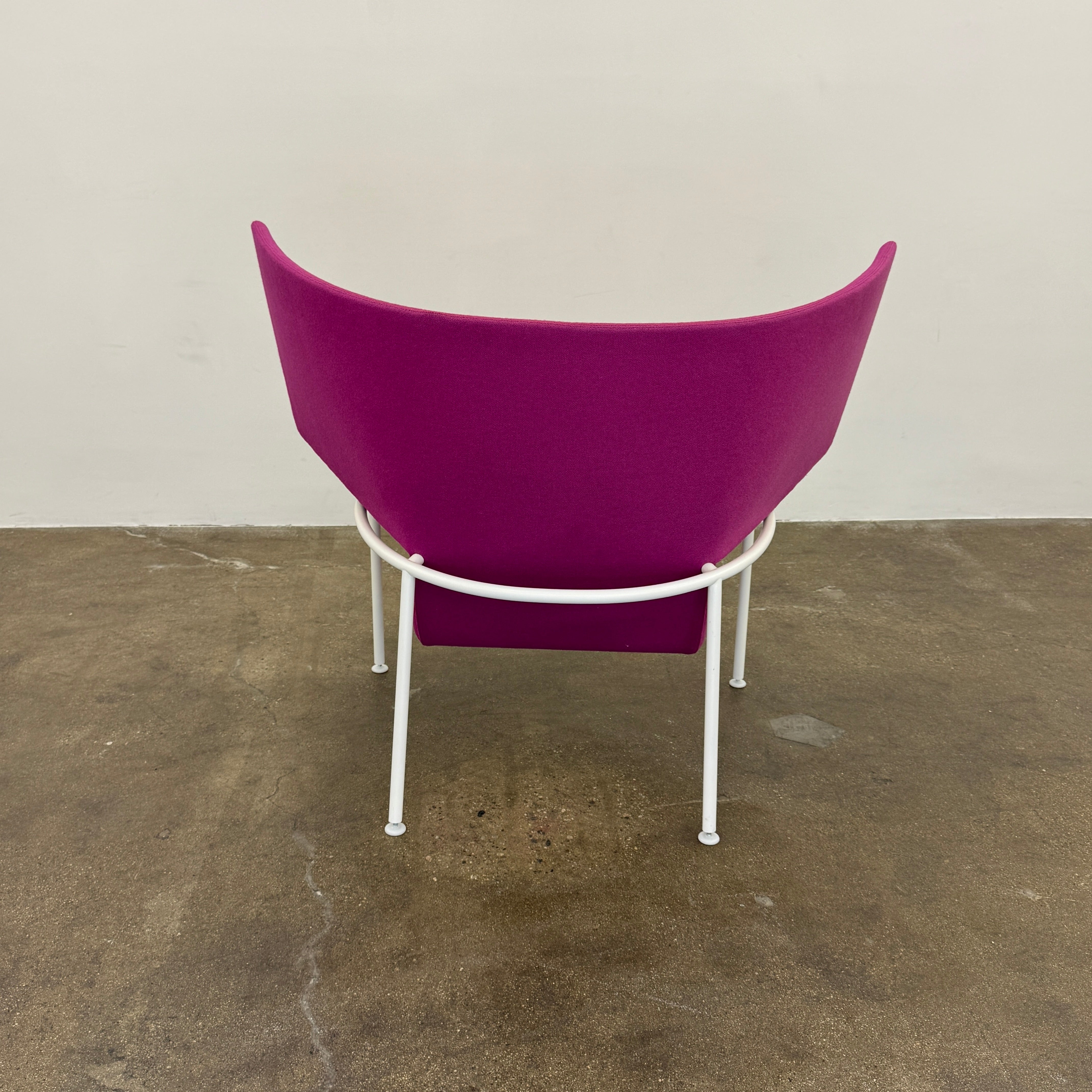 The Cappellini Capo Chair by Cappellini features a modern design with bright magenta upholstery, an angular backrest, and white metal legs, set against a plain white background.