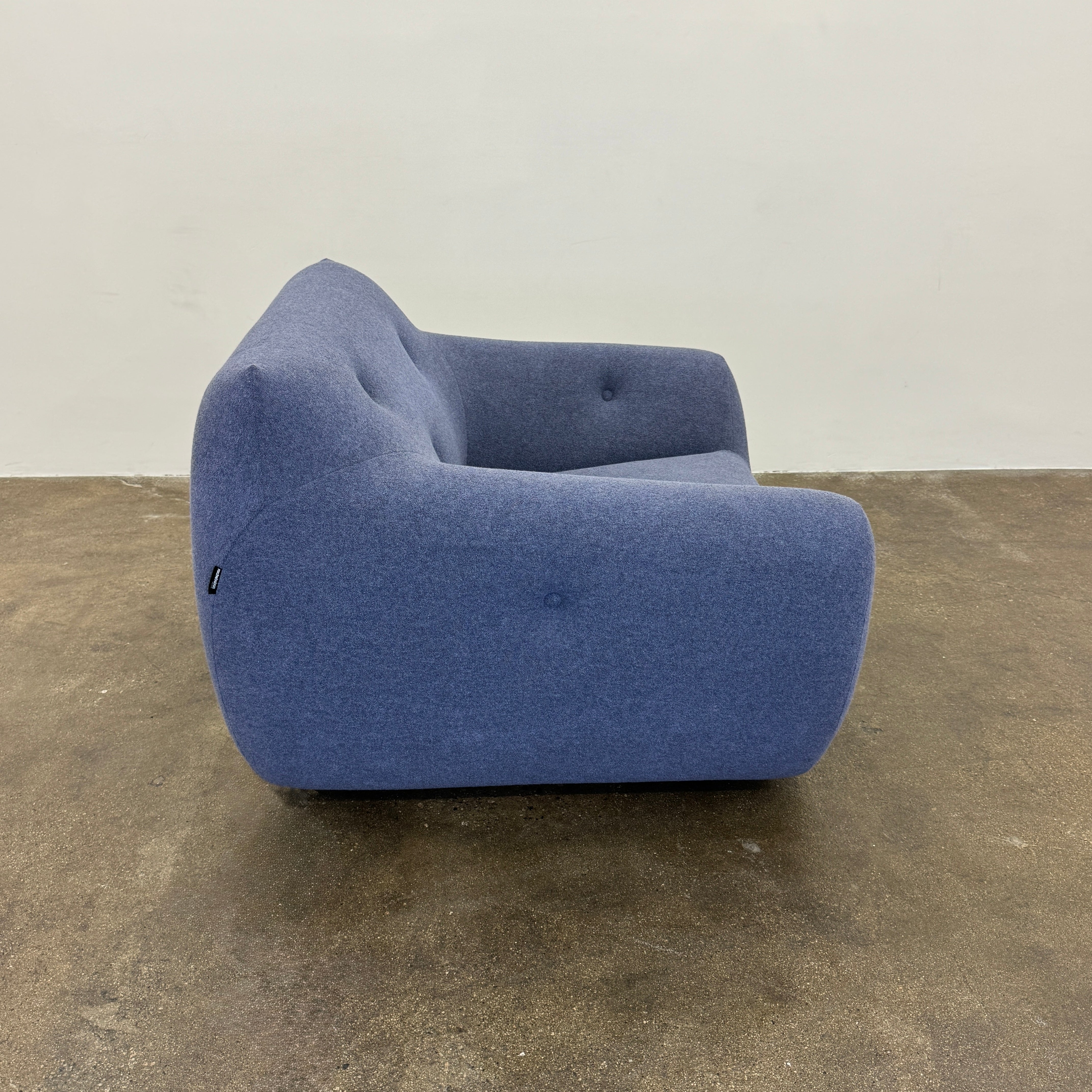 The Roche Bobois Informel Outdoor Armchair Low Back - Bleuet is a modern blue armchair with tufted buttons and plush comfort, shown against a white background.