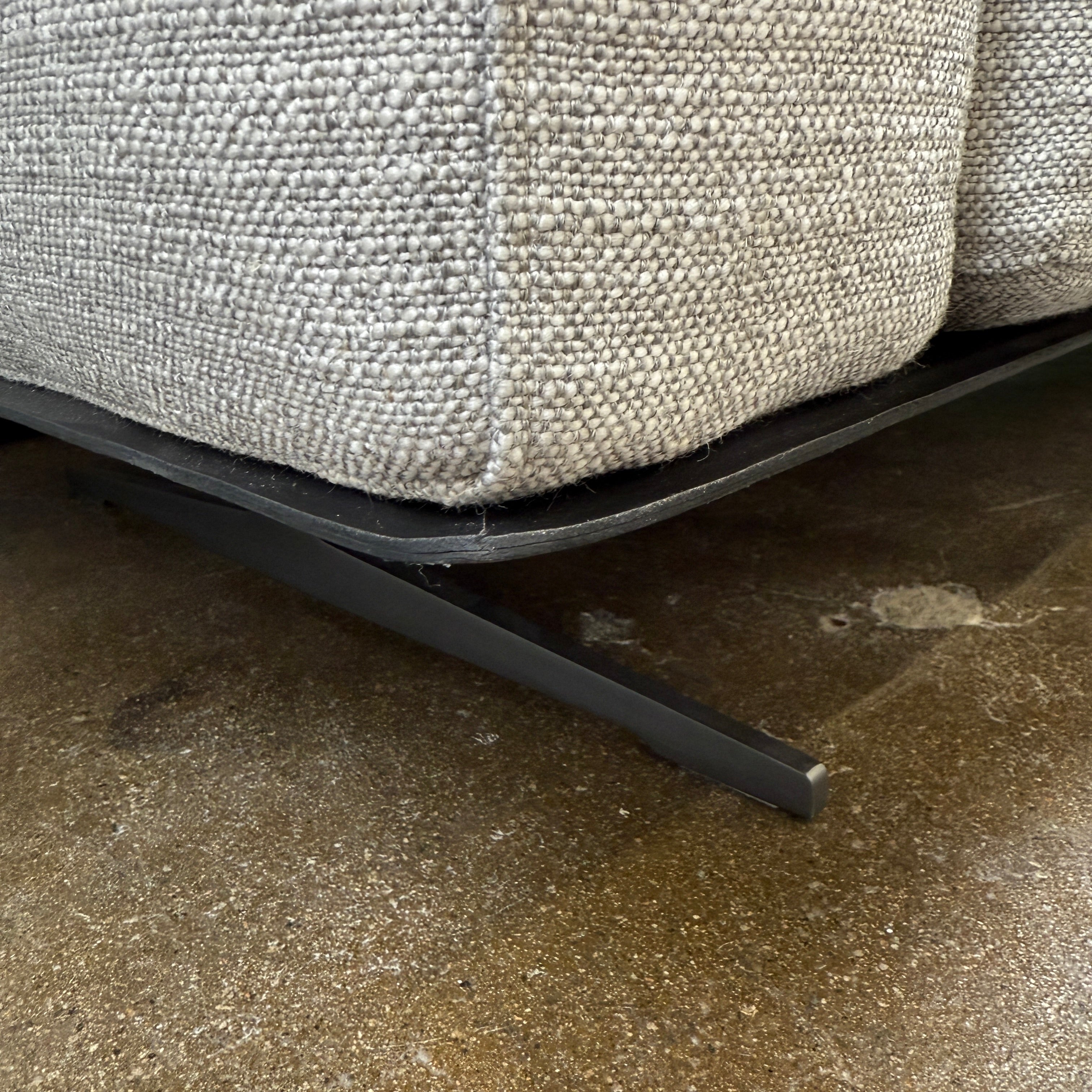 A contemporary Flexform Dream Sofa in light gray, featuring wide armrests and black metal legs, is displayed against a plain white background.