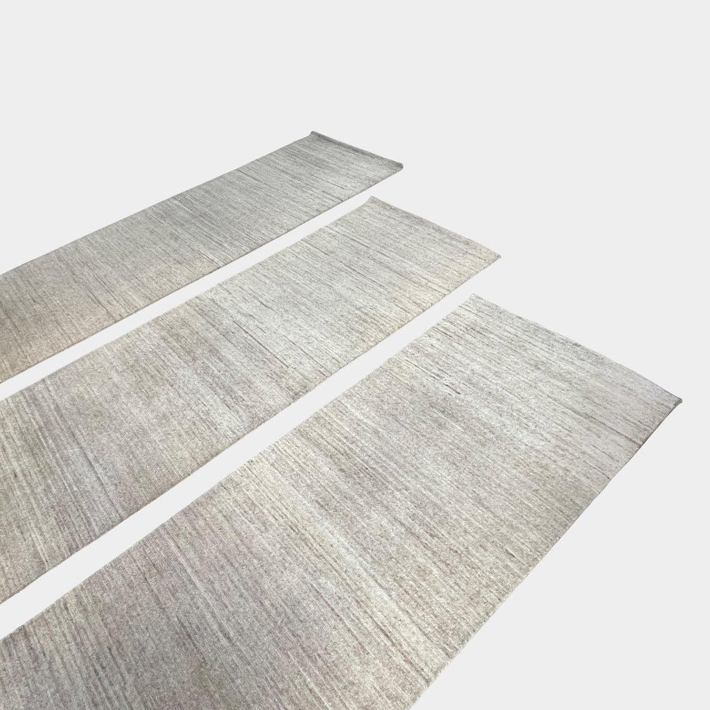 Three beige Delinear wool runners with dark borders on a concrete floor in a garage setting.