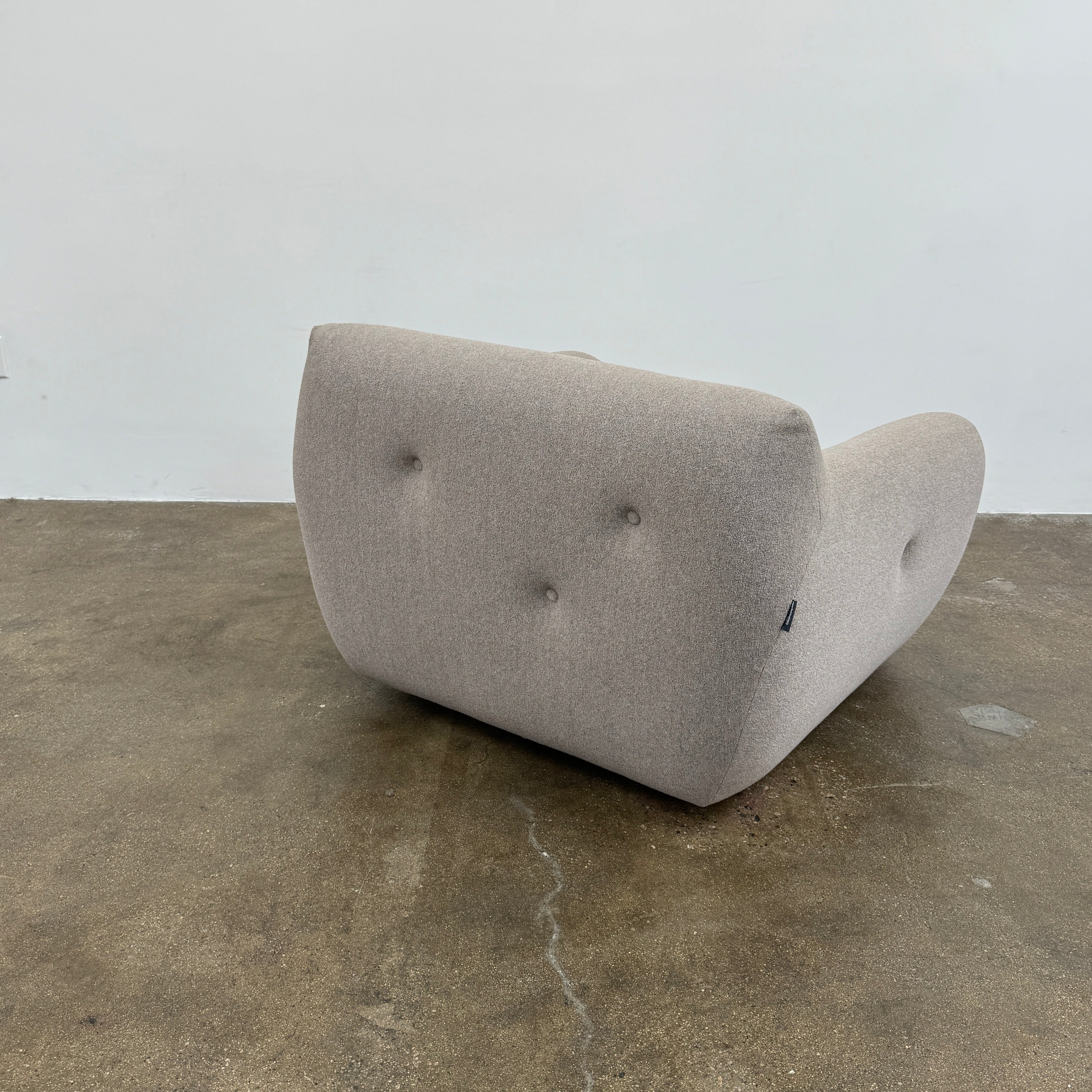 The Roche Bobois Informel Outdoor Low Back Armchair by Roche Bobois features modern, light gray upholstery with rounded arms and tufted button details for plush comfort, shown from the front on a white background.