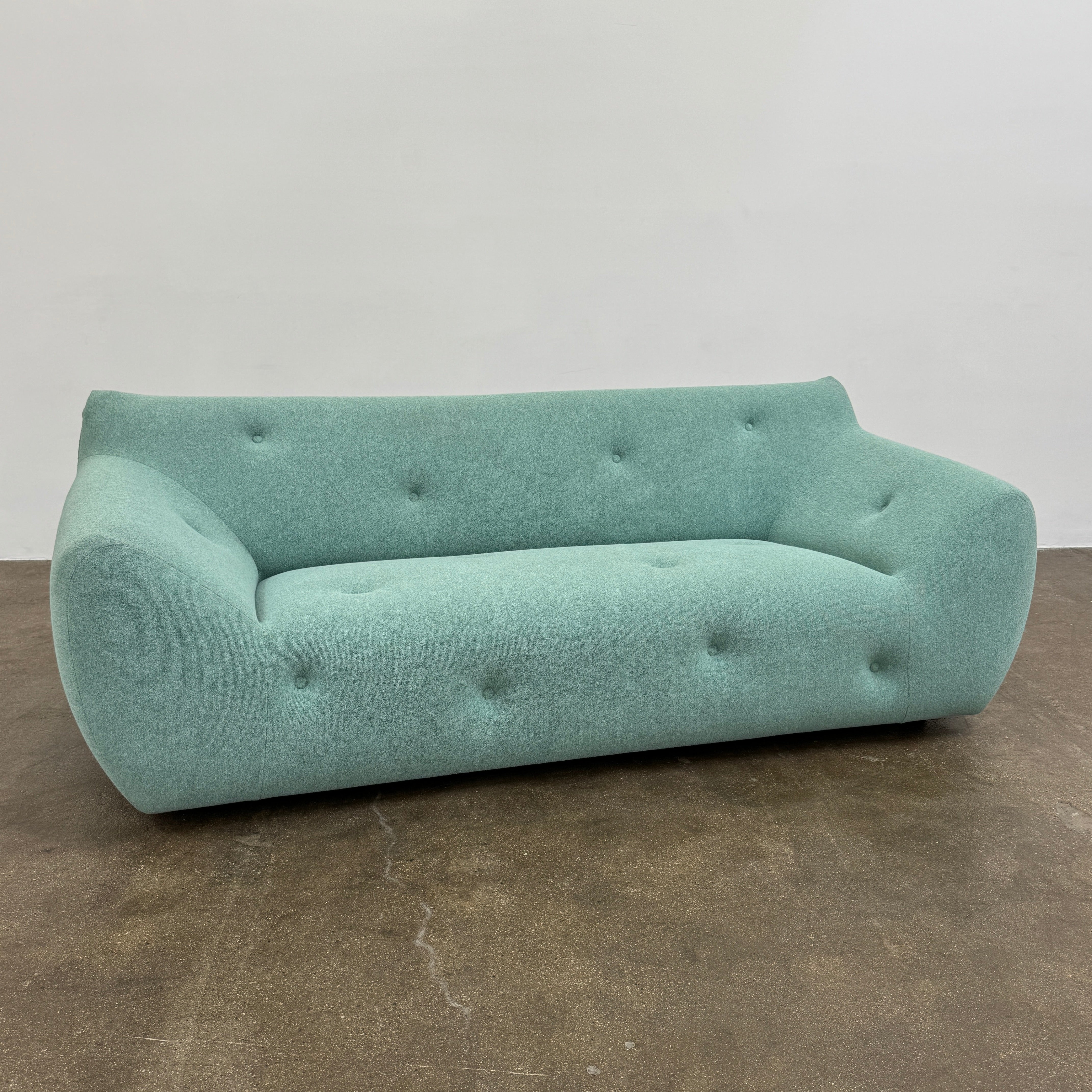 The Roche Bobois Informel Outdoor Large 3-seat Sofa Low Back features a light teal modern design with rounded edges, button-tufted details, and advanced outdoor fabric technology, inspired by Roche Bobois’s signature style.