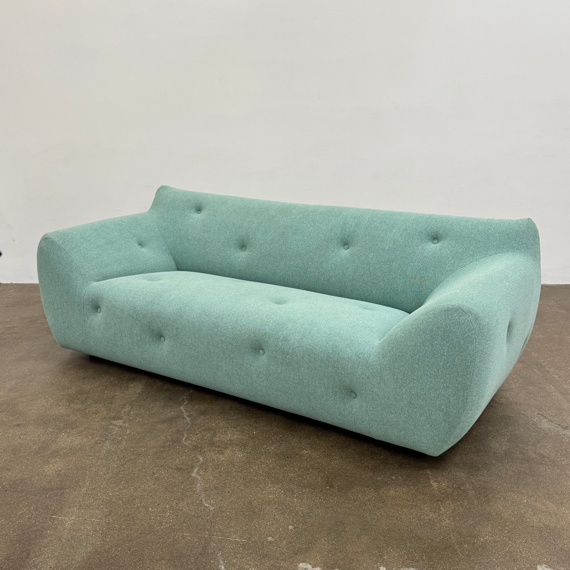 The Roche Bobois Informel Outdoor Large 3-seat Sofa Low Back features a light teal modern design with rounded edges, button-tufted details, and advanced outdoor fabric technology, inspired by Roche Bobois’s signature style.